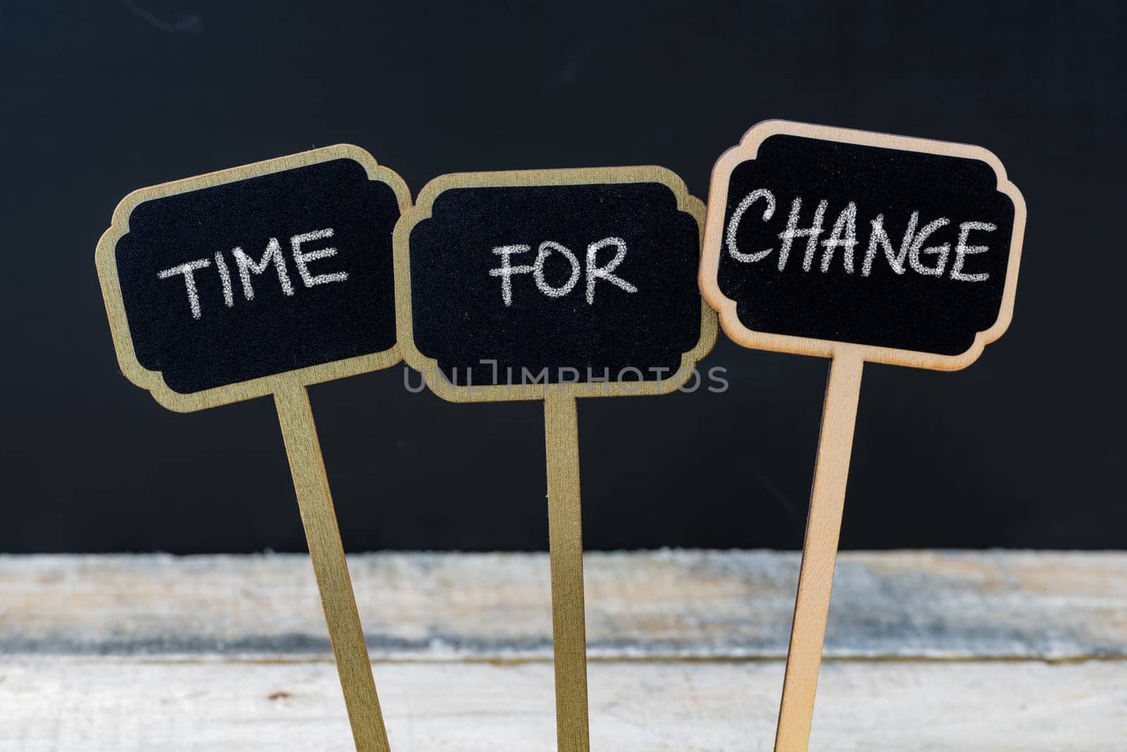 Business message TIME FOR CHANGE written with chalk on wooden mini blackboard labels, defocused chalkboard and wood table in background