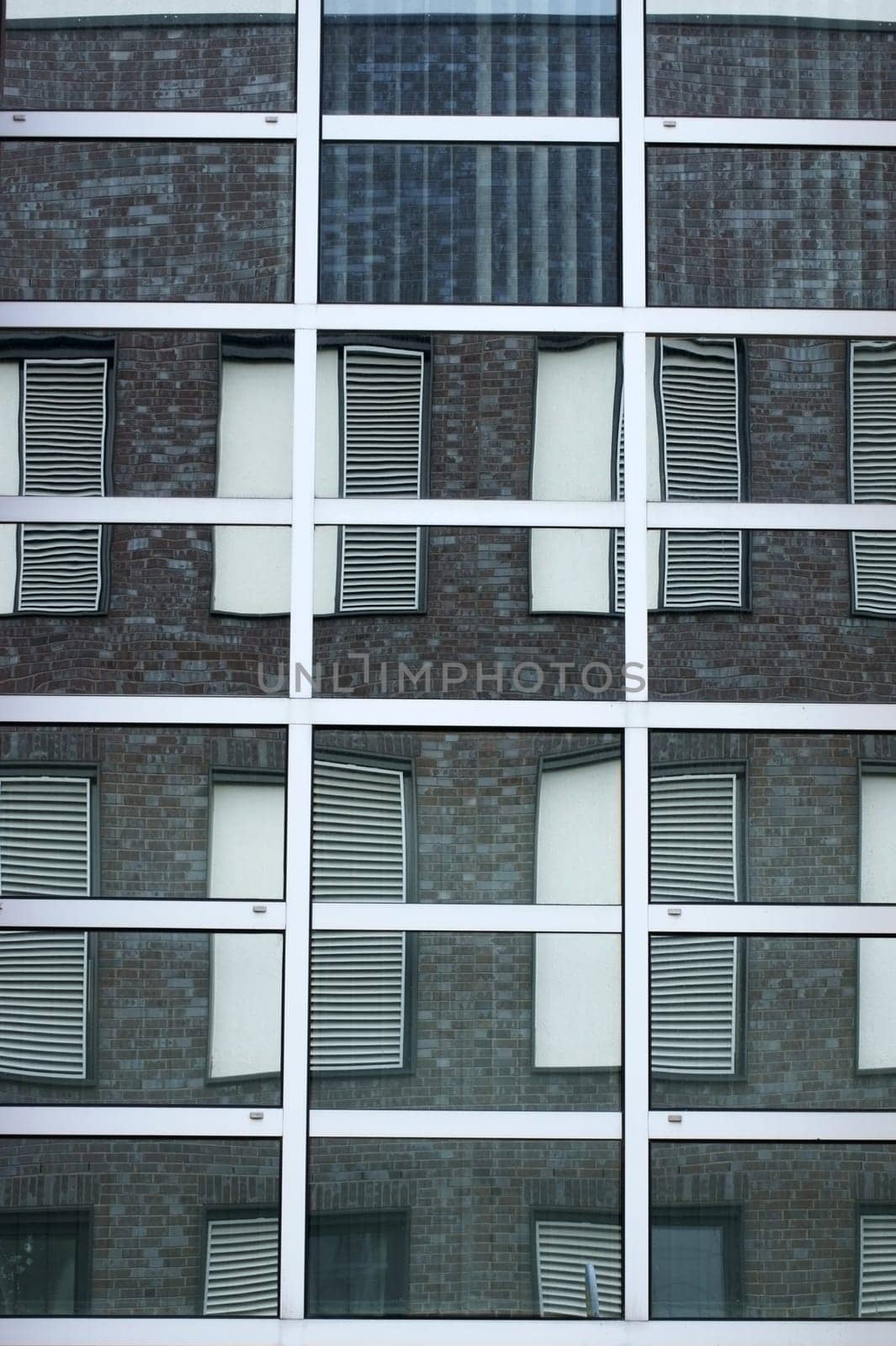 The abstract reflection of windows with shutters in mirrored windows.