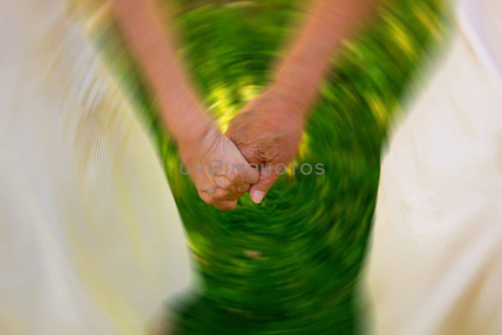 Concept shoot of friendship and love of old man and woman: two hands over green grass