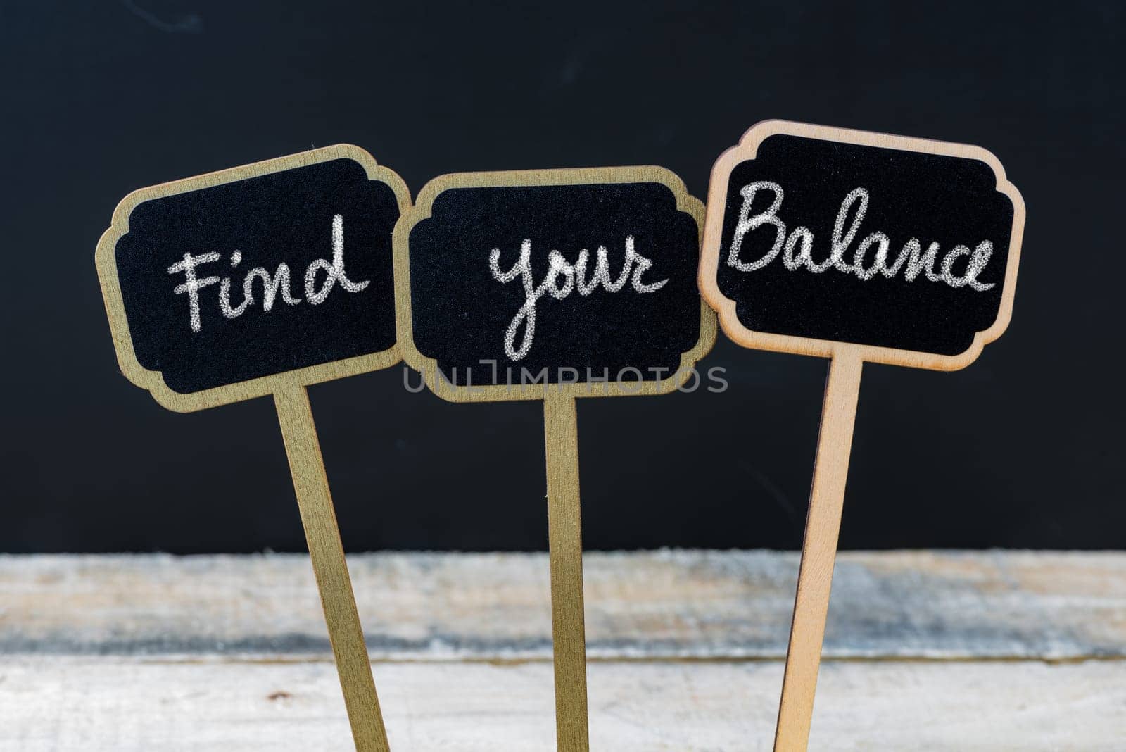 Motivational message Find Your Balance written with chalk on wooden mini blackboard labels, defocused chalkboard and wood table in background