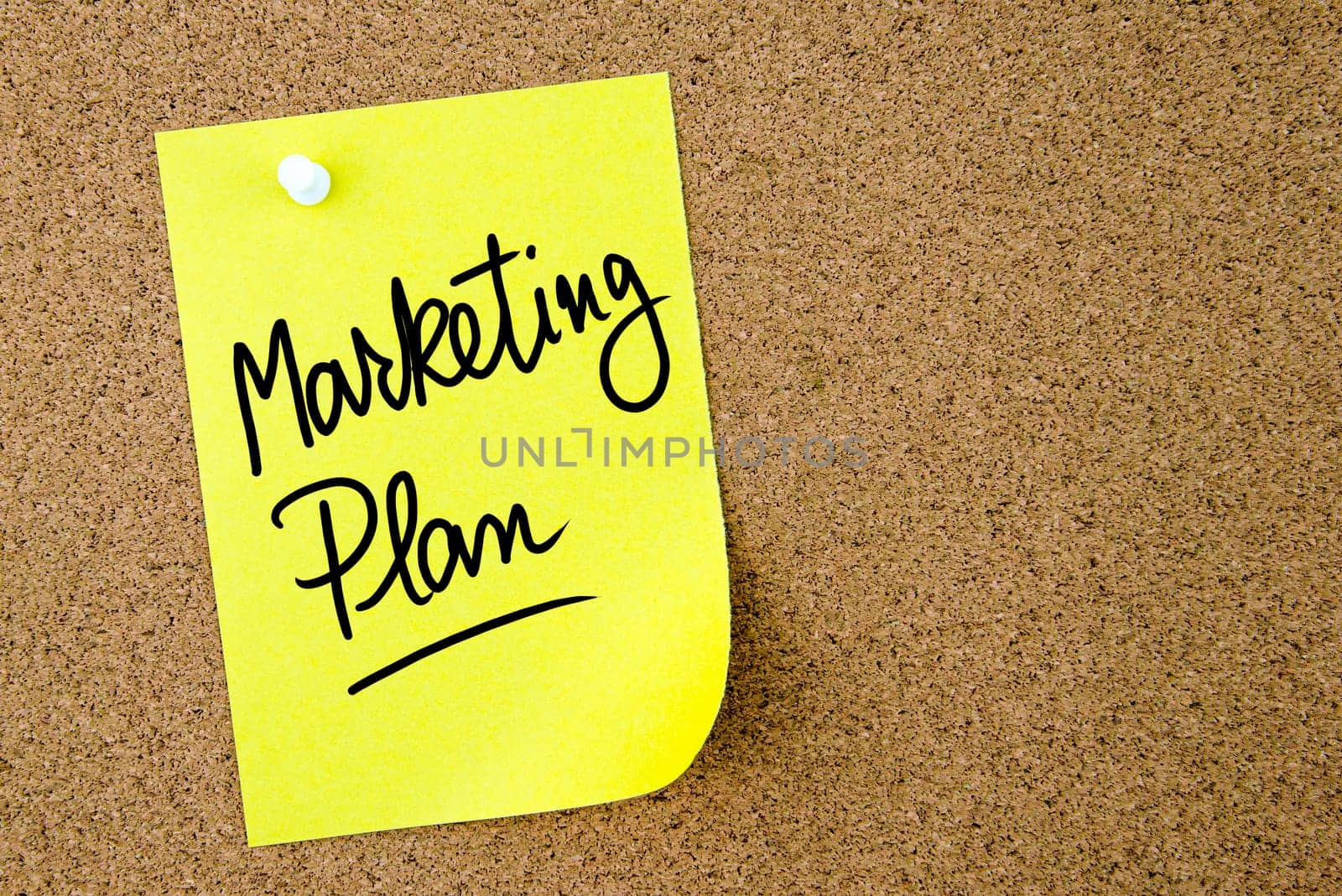 Marketing Plan text written on yellow paper note pinned on cork board with white thumbtack. Business concept image with copy space available