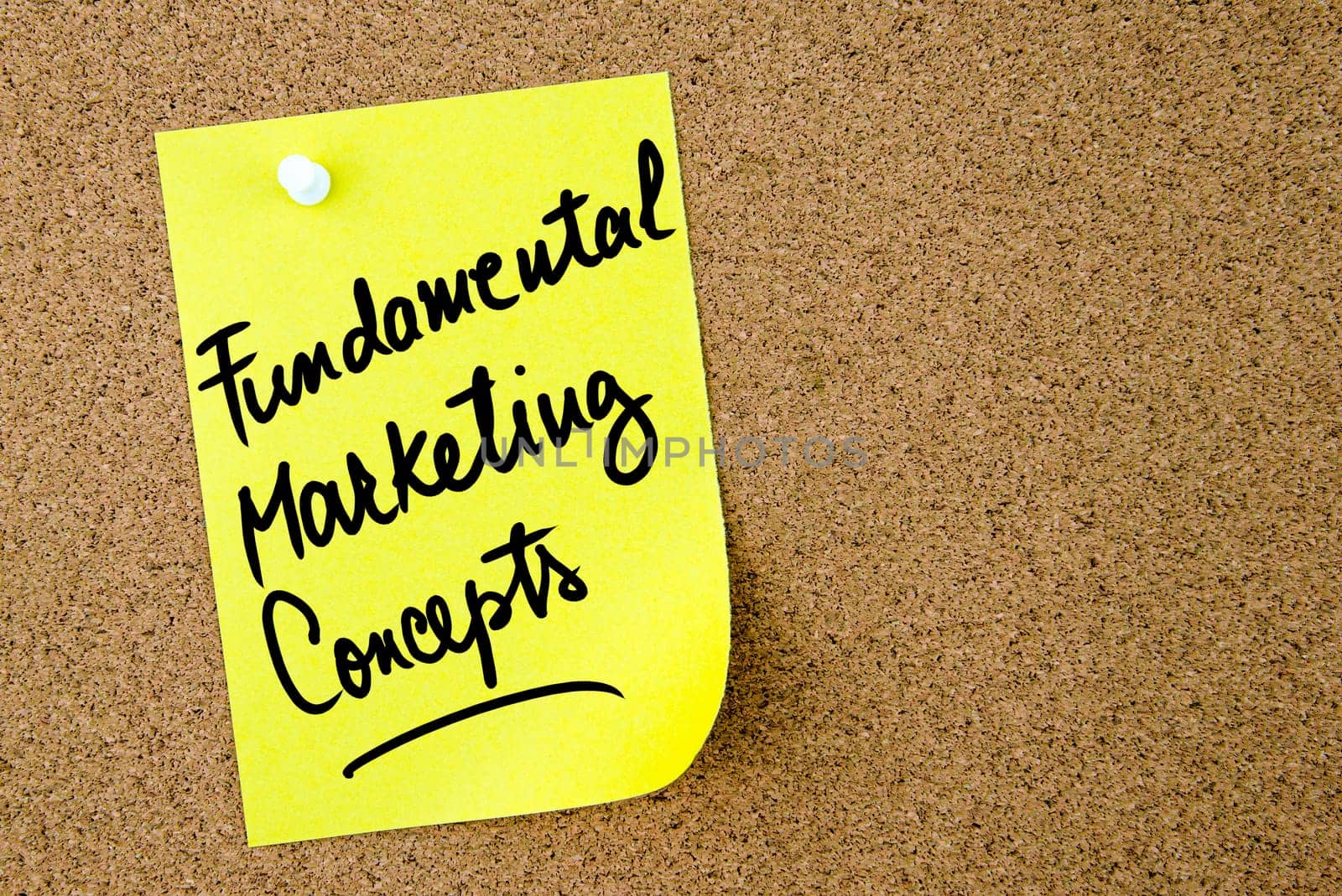 Fundamental Marketing Concepts text written on yellow paper note pinned on cork board with white thumbtack. Business concept image with copy space available