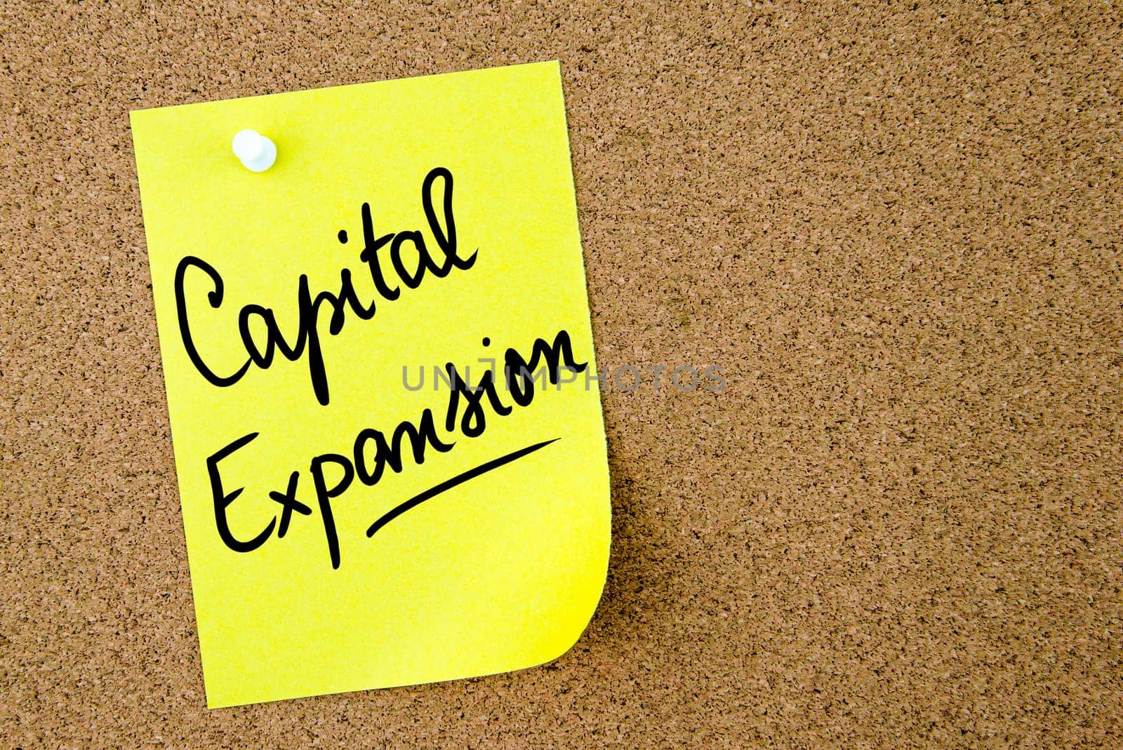 Capital Expansion text written on yellow paper note pinned on cork board with white thumbtack. Business concept image with copy space available