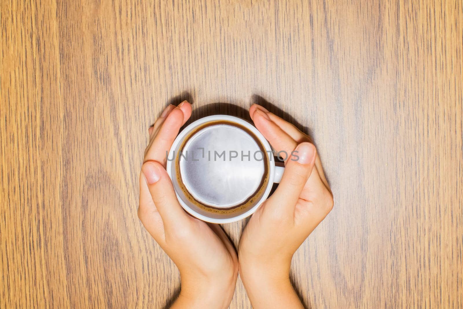 Female hands holding cup of coffee on wooden background