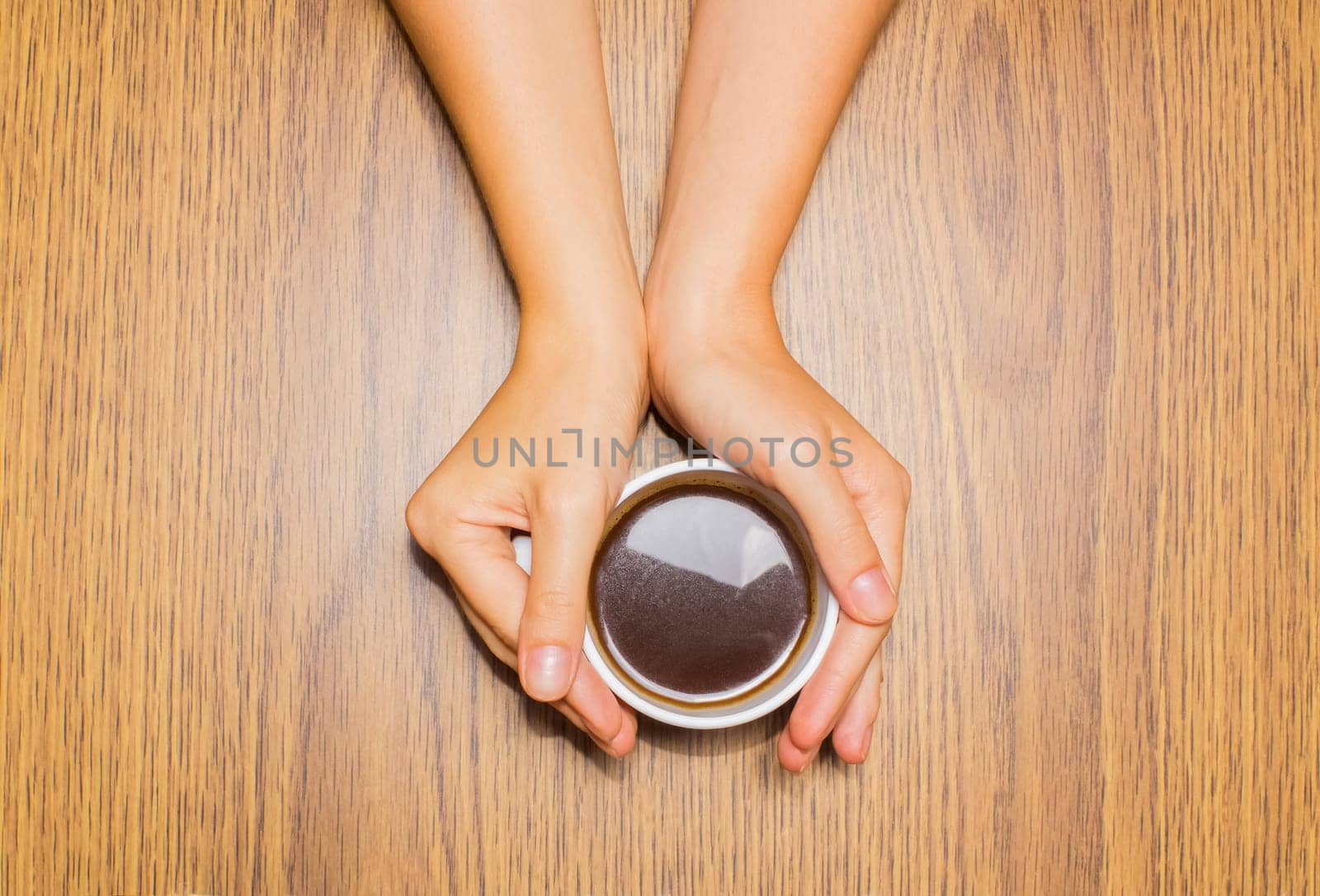 Female hands holding cup of coffee on wooden background