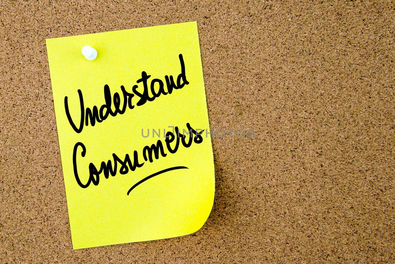 Understand Consumers text written on yellow paper note pinned on cork board with white thumbtack. Business concept image with copy space available