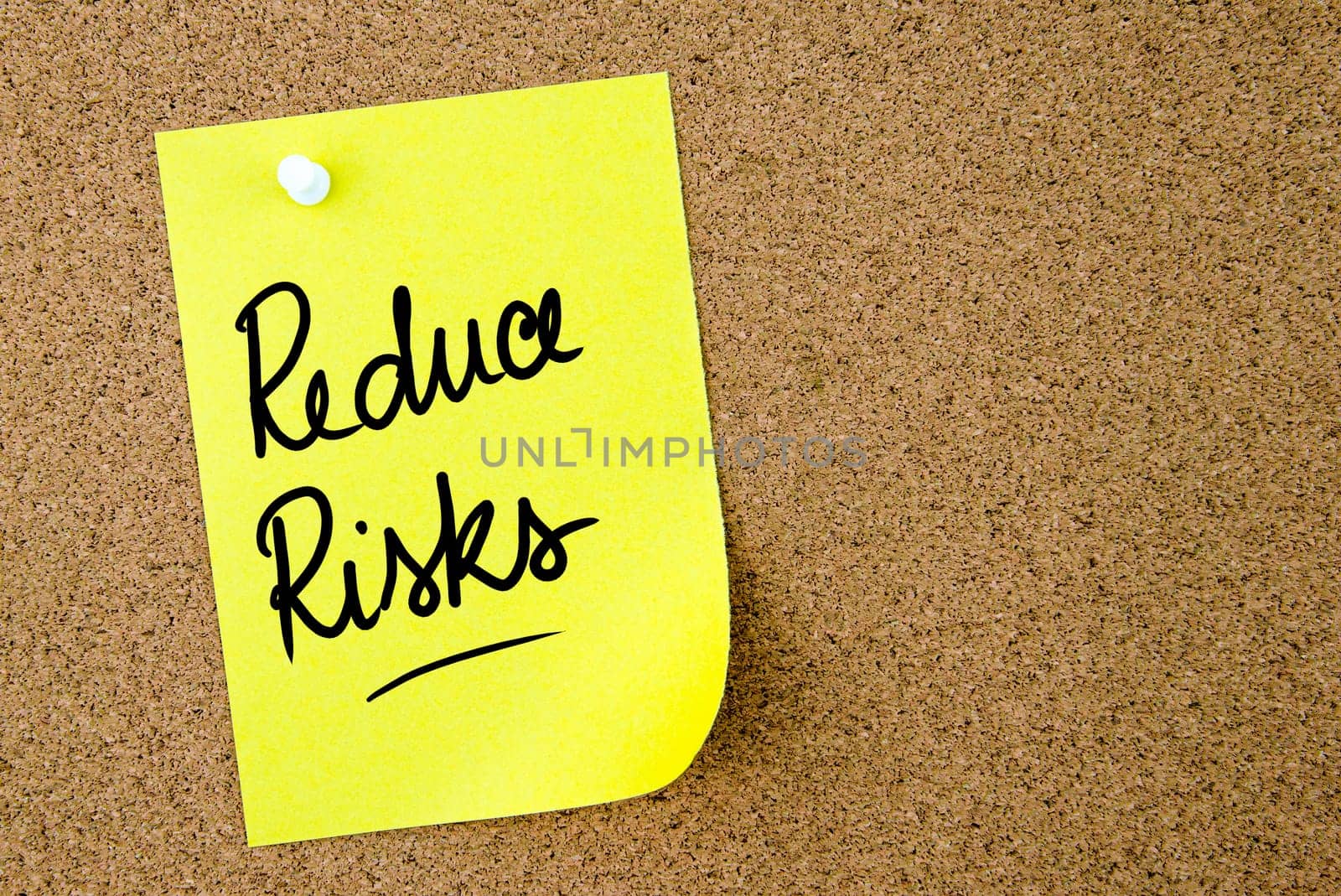 Reduce Risks text written on yellow paper note pinned on cork board with white thumbtack. Business concept image with copy space available