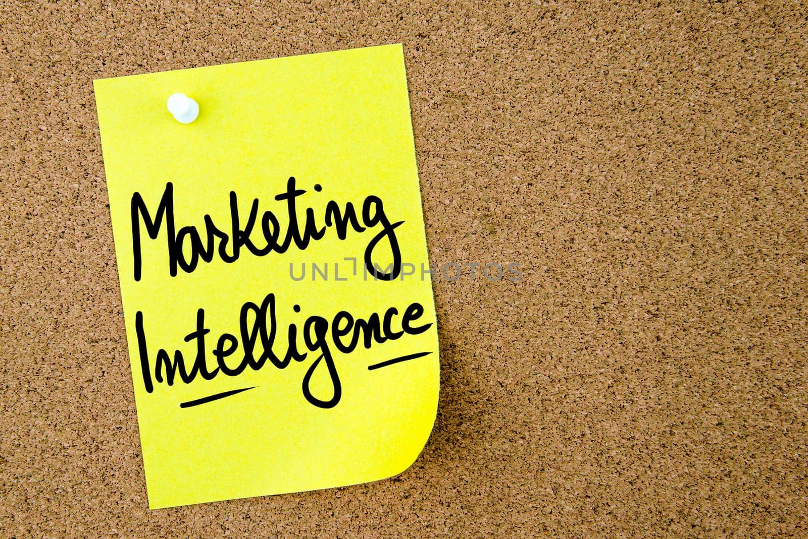 Marketing Intelligence text written on yellow paper note pinned on cork board with white thumbtack. Business concept image with copy space available