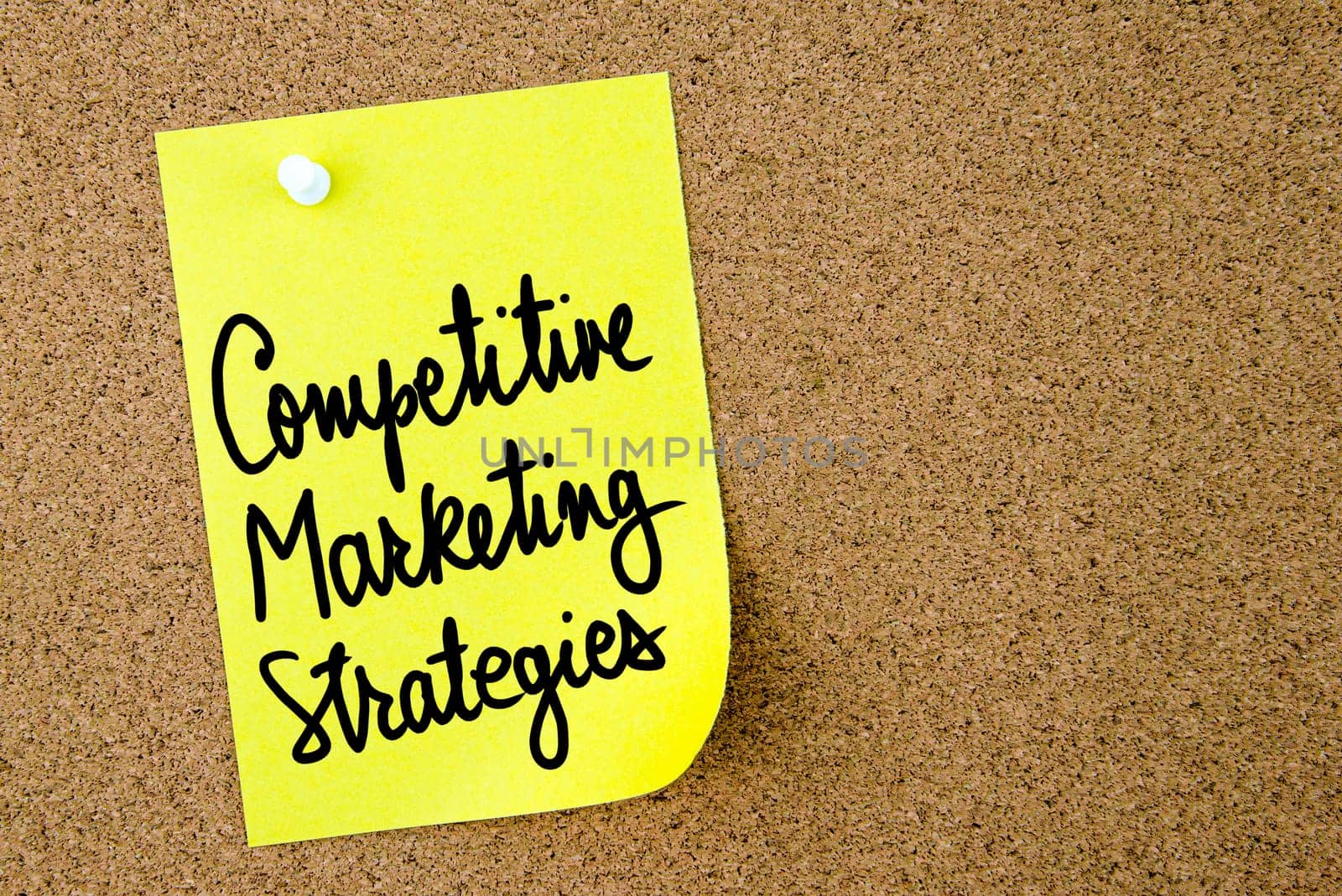 Competitive Marketing Strategies text written on yellow paper note pinned on cork board with white thumbtack. Business concept image with copy space available