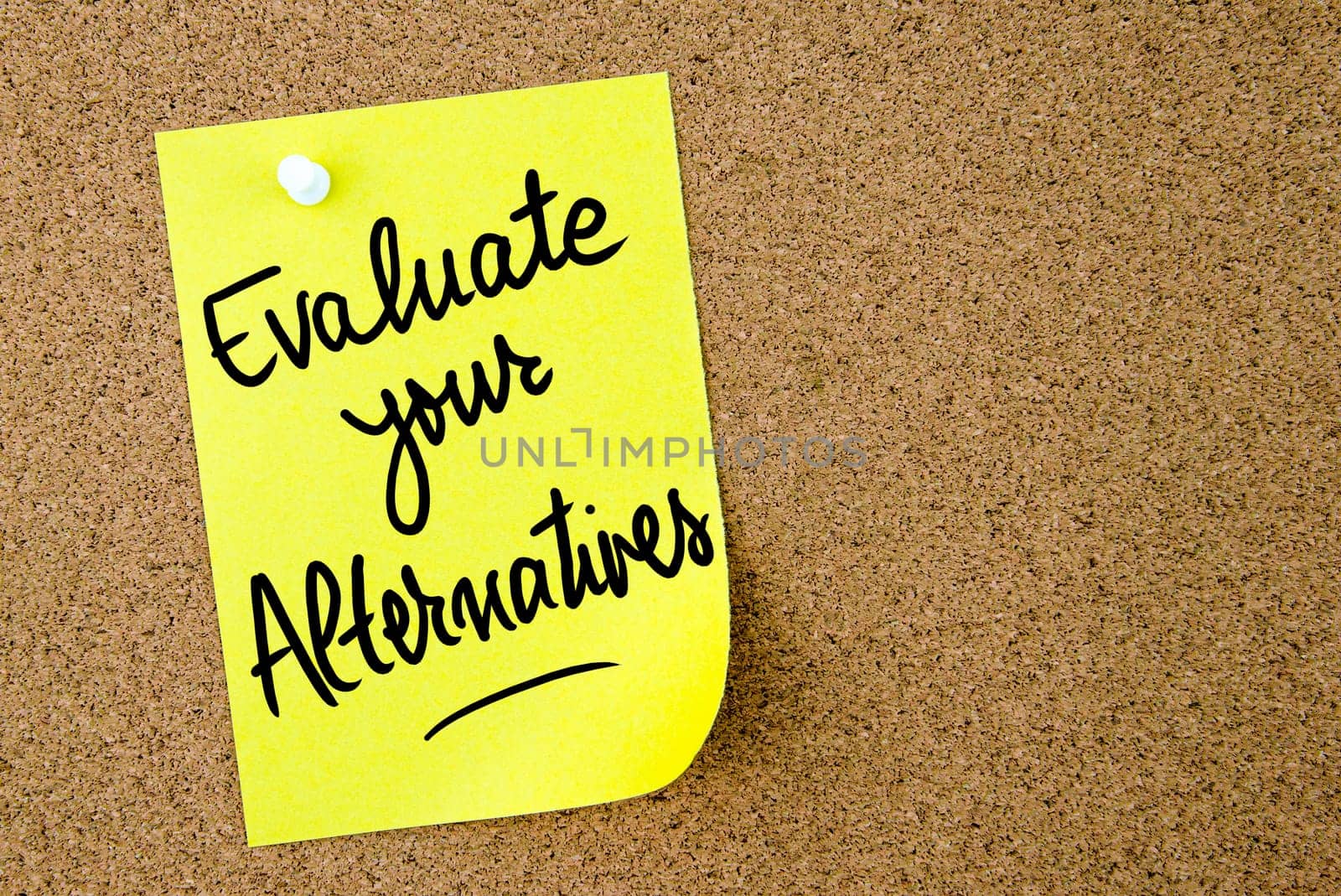 Evaluate Your Alternatives text written on yellow paper note pinned on cork board with white thumbtack. Business concept image with copy space available