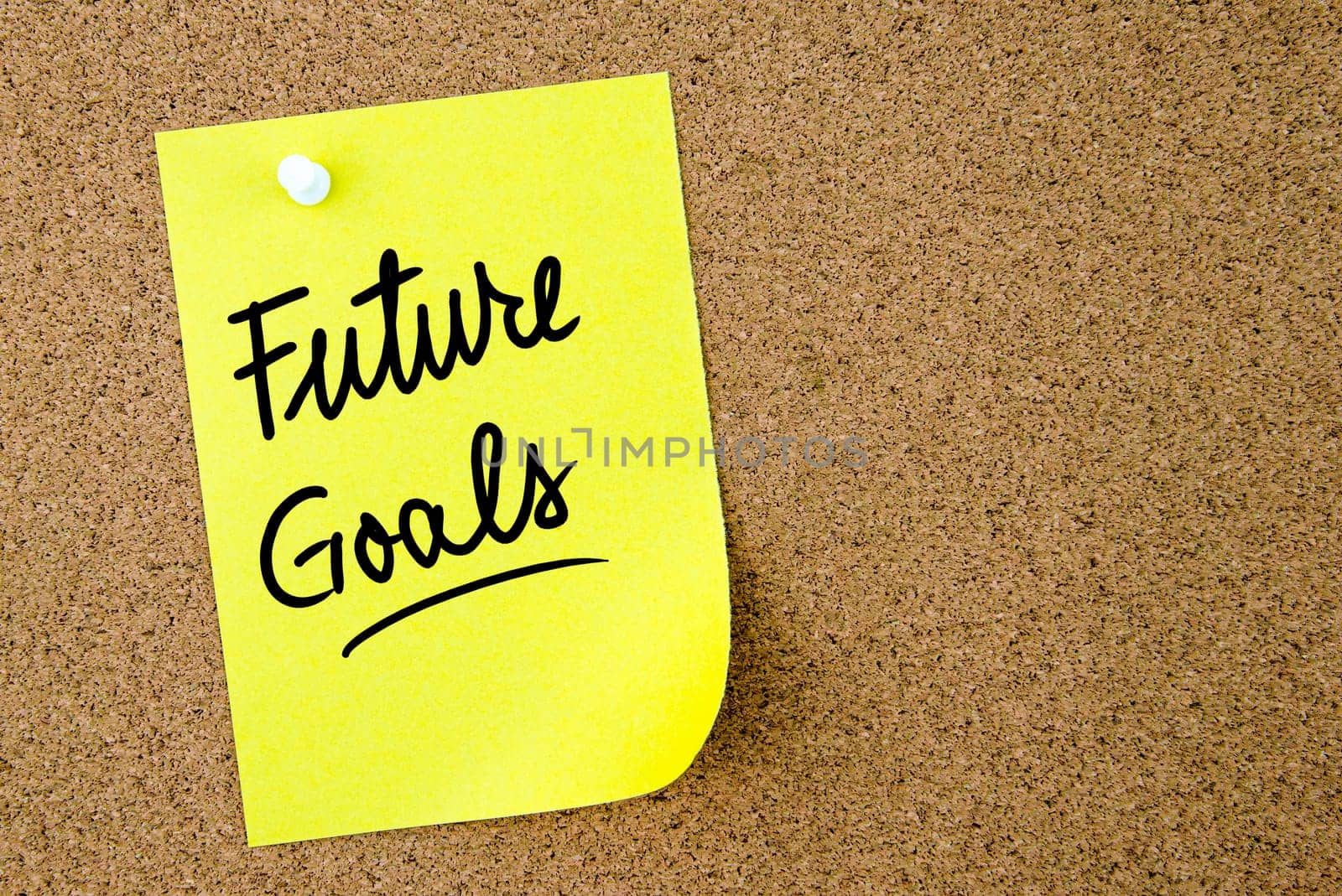 Future Goals text written on yellow paper note pinned on cork board with white thumbtack. Business concept image with copy space available