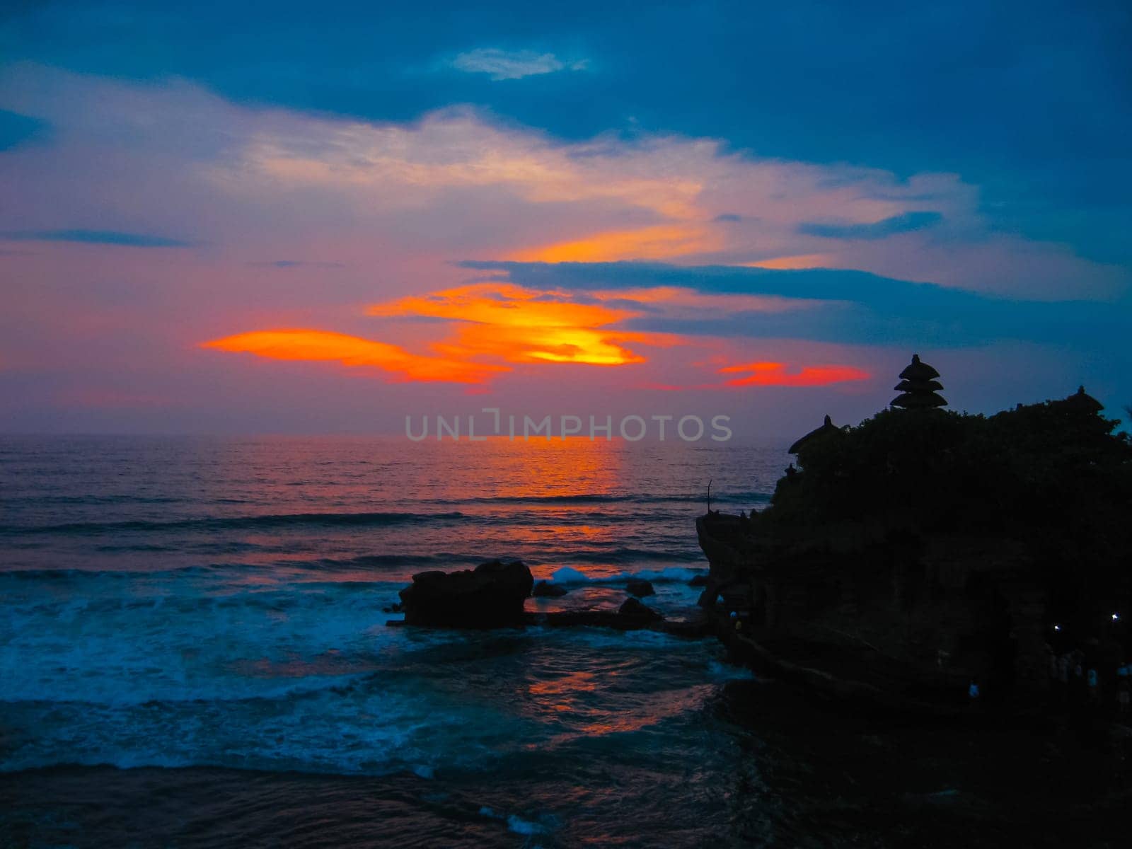 Tanah Lot and sea waves in golden sunset at Bali