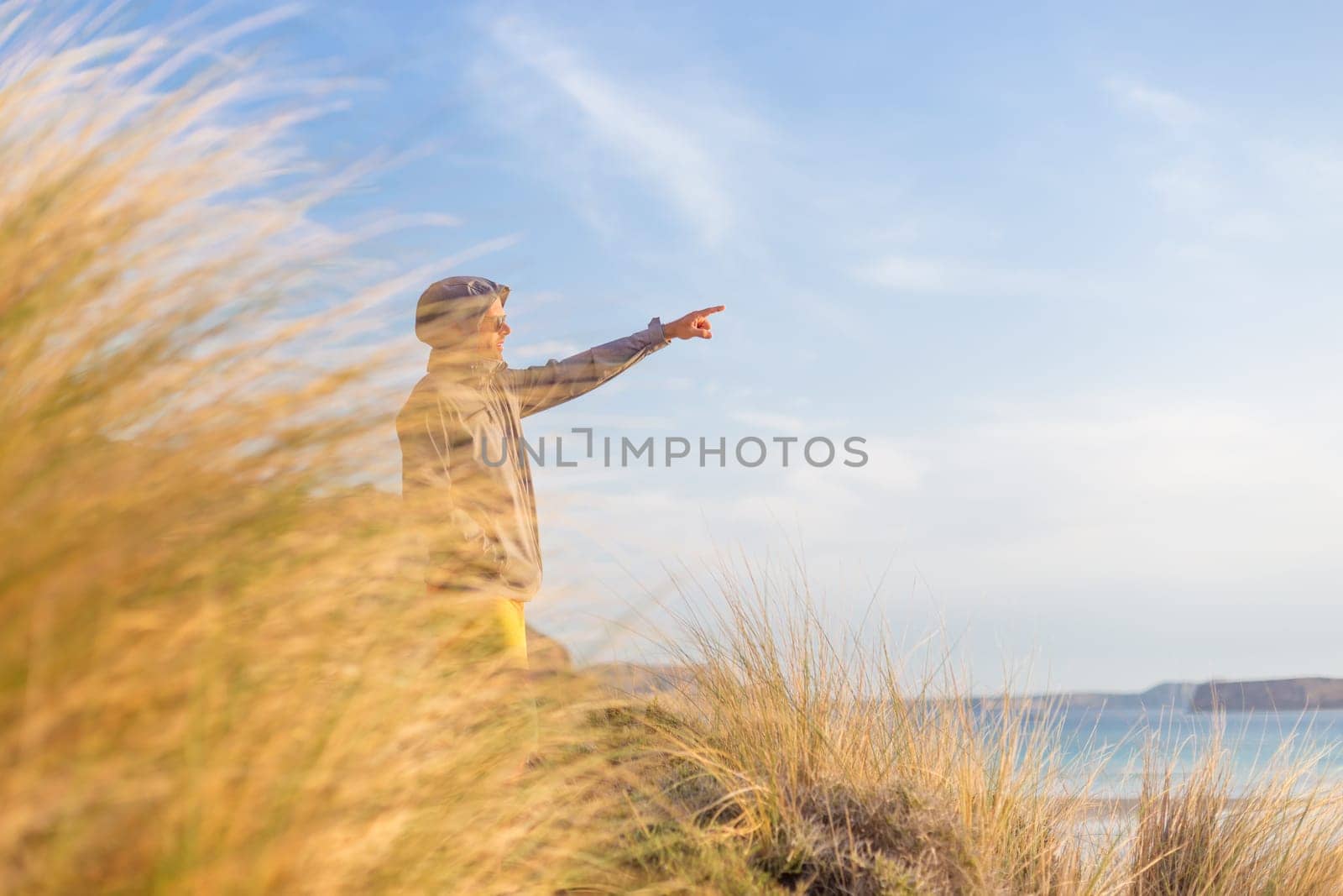 Sporty active man pointing hand on horizon, enjoying beauty of nature, freedom and life at beautiful landscape. Active lifestyle outdoors.