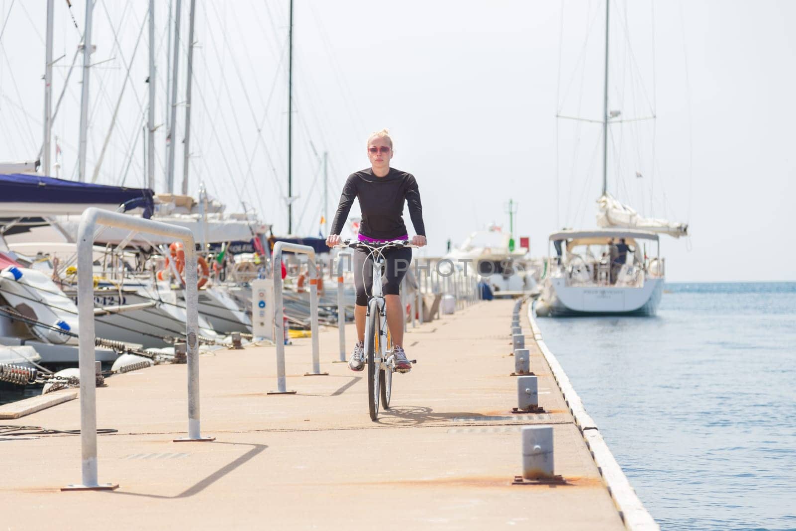 Young active woman cycling on pier in Rovinj marina, Istria, Croatia