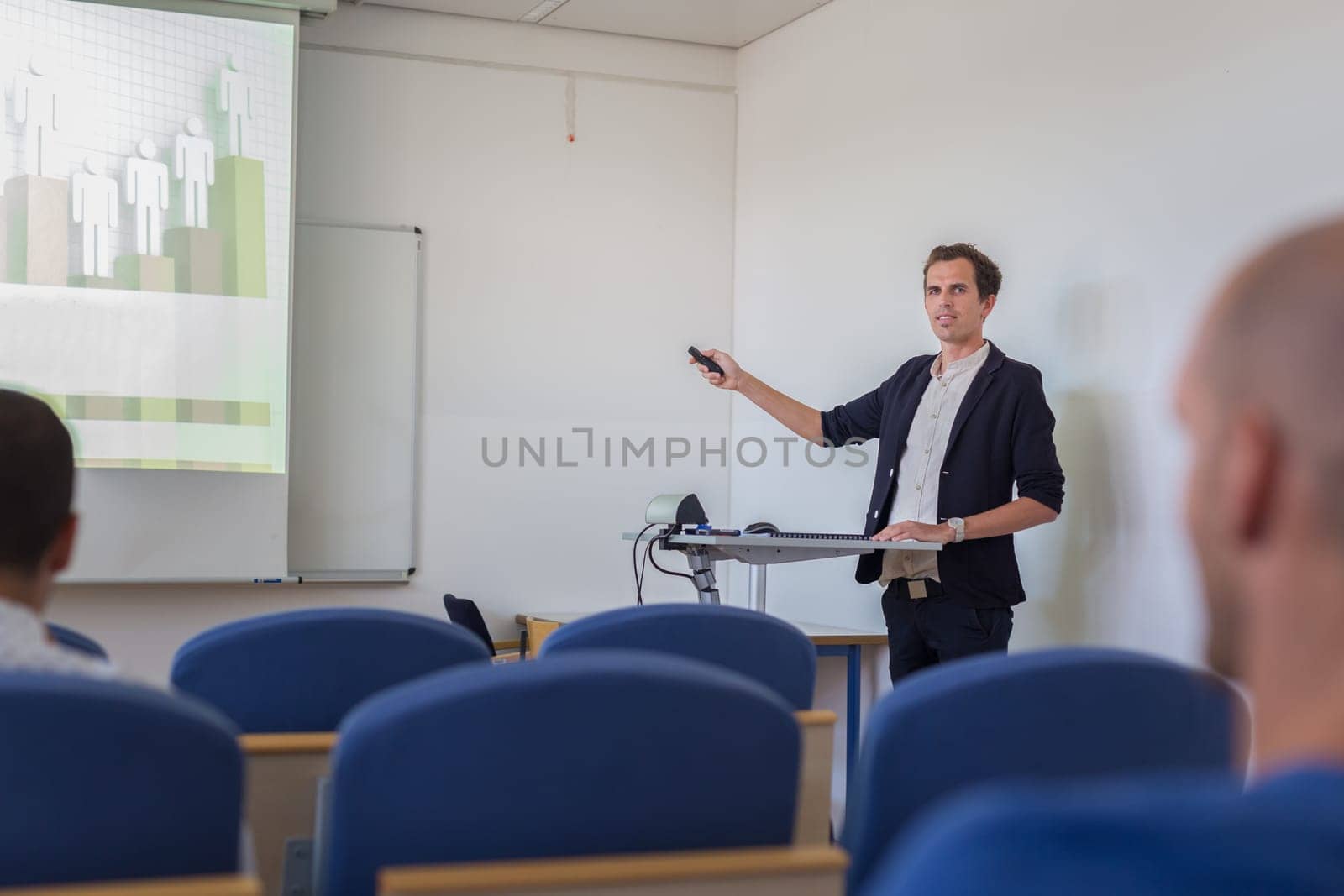 Relaxed confident smart student presenting his study work in front of whiteboard, defending his thesis. Doctoral thesis defense on faculty.