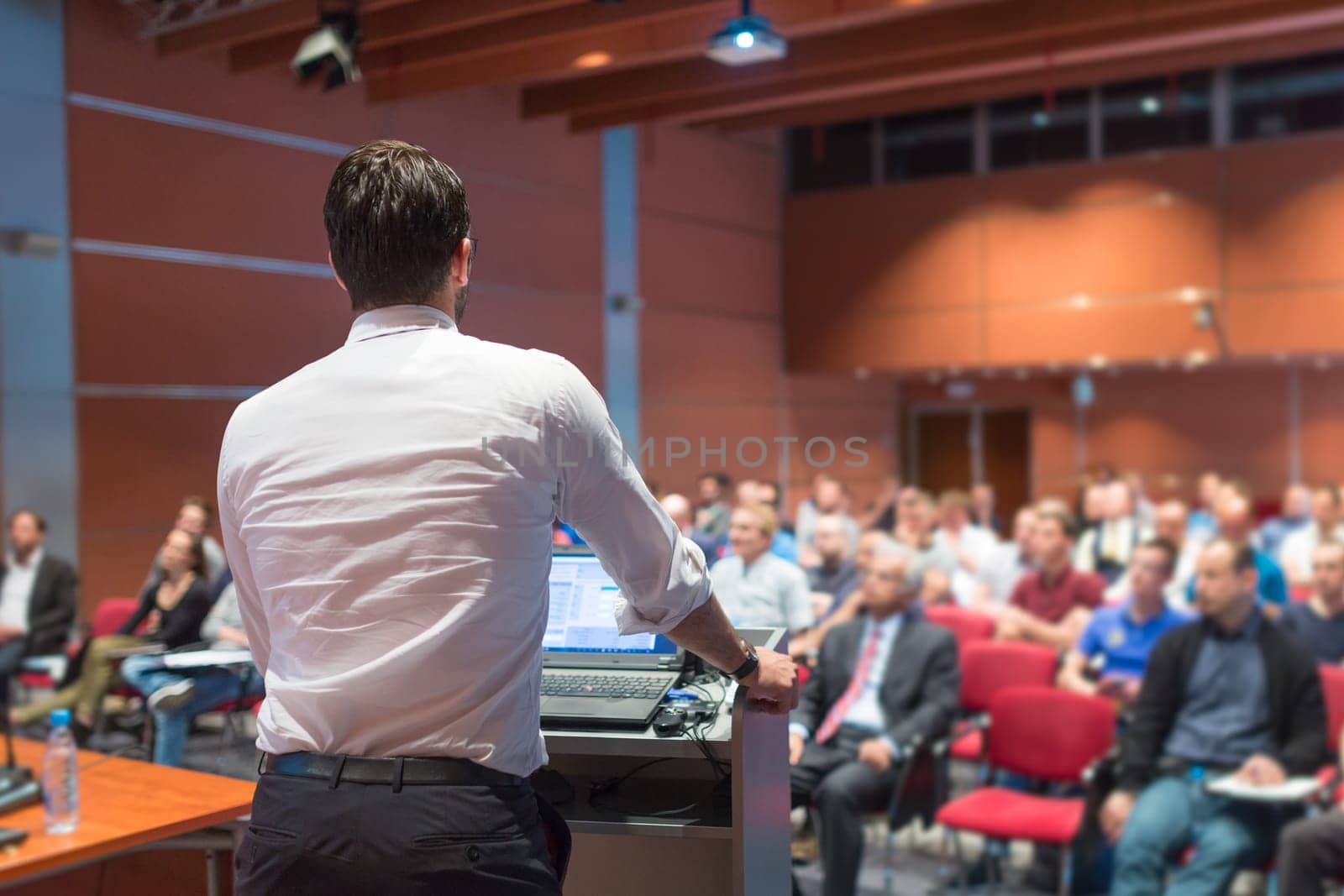 Speaker giving a talk on corporate Business Conference. Audience at the conference hall. Business and Entrepreneurship event.