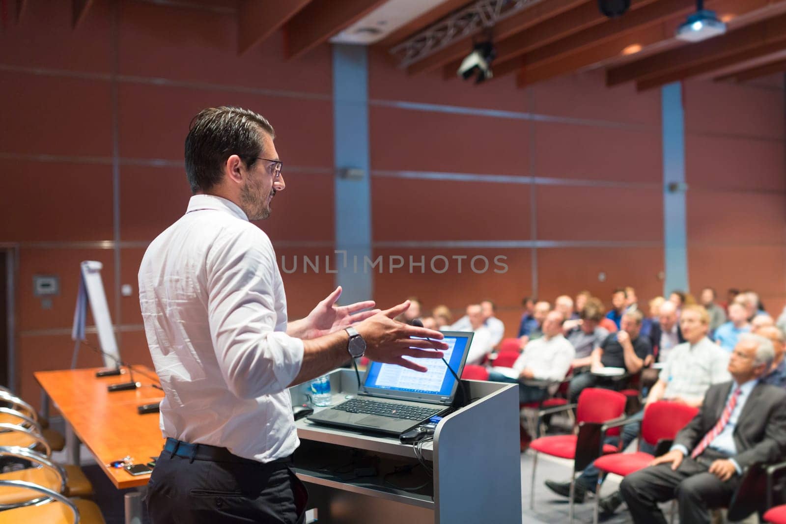Speaker giving a talk on corporate Business Conference. Audience at the conference hall. Business and Entrepreneurship event.