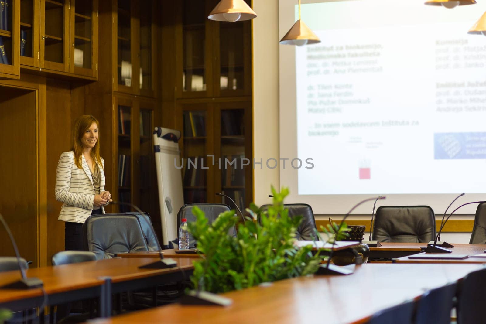 Doctoral thesis defense on faculty. Relaxed confident smart female student presenting hes study work in front of whiteboard to commission, defending hes thesis. Could also be job interview.