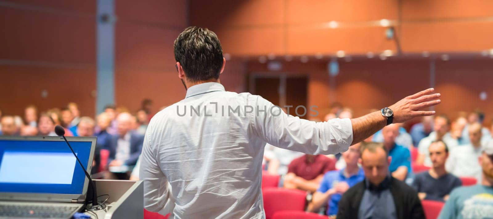 Speaker giving a talk on corporate Business Conference. Audience at the conference hall. Business and Entrepreneurship event.