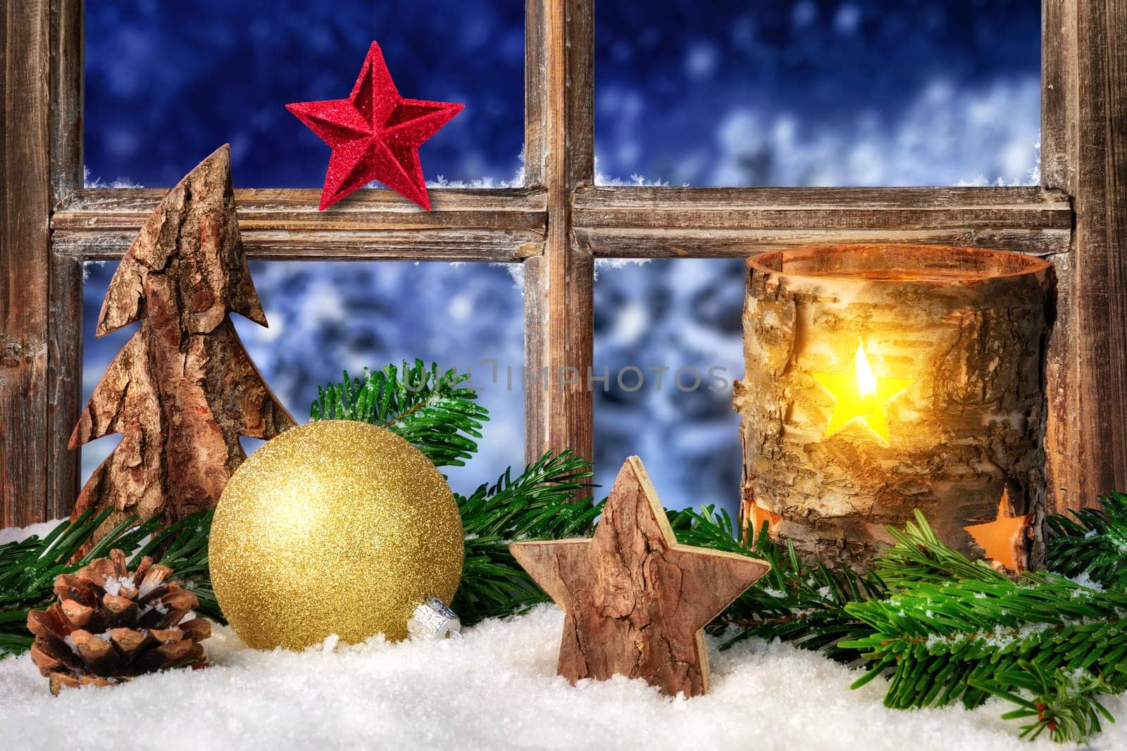Christmas,Advent or winter seasonal arrangement on a window sill in cozy candle light,decorated with snow,ornaments and fir branches