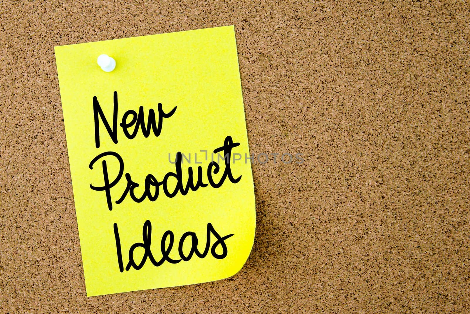 New Product Ideas text written on yellow paper note pinned on cork board with white thumbtack. Business concept image with copy space available