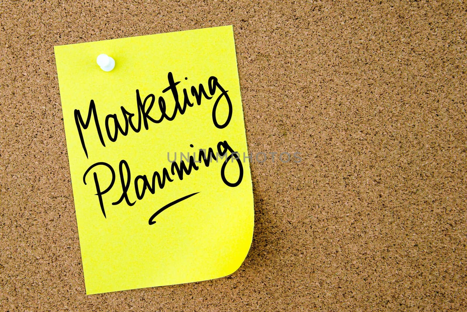 Marketing Planning text written on yellow paper note pinned on cork board with white thumbtack. Business concept image with copy space available