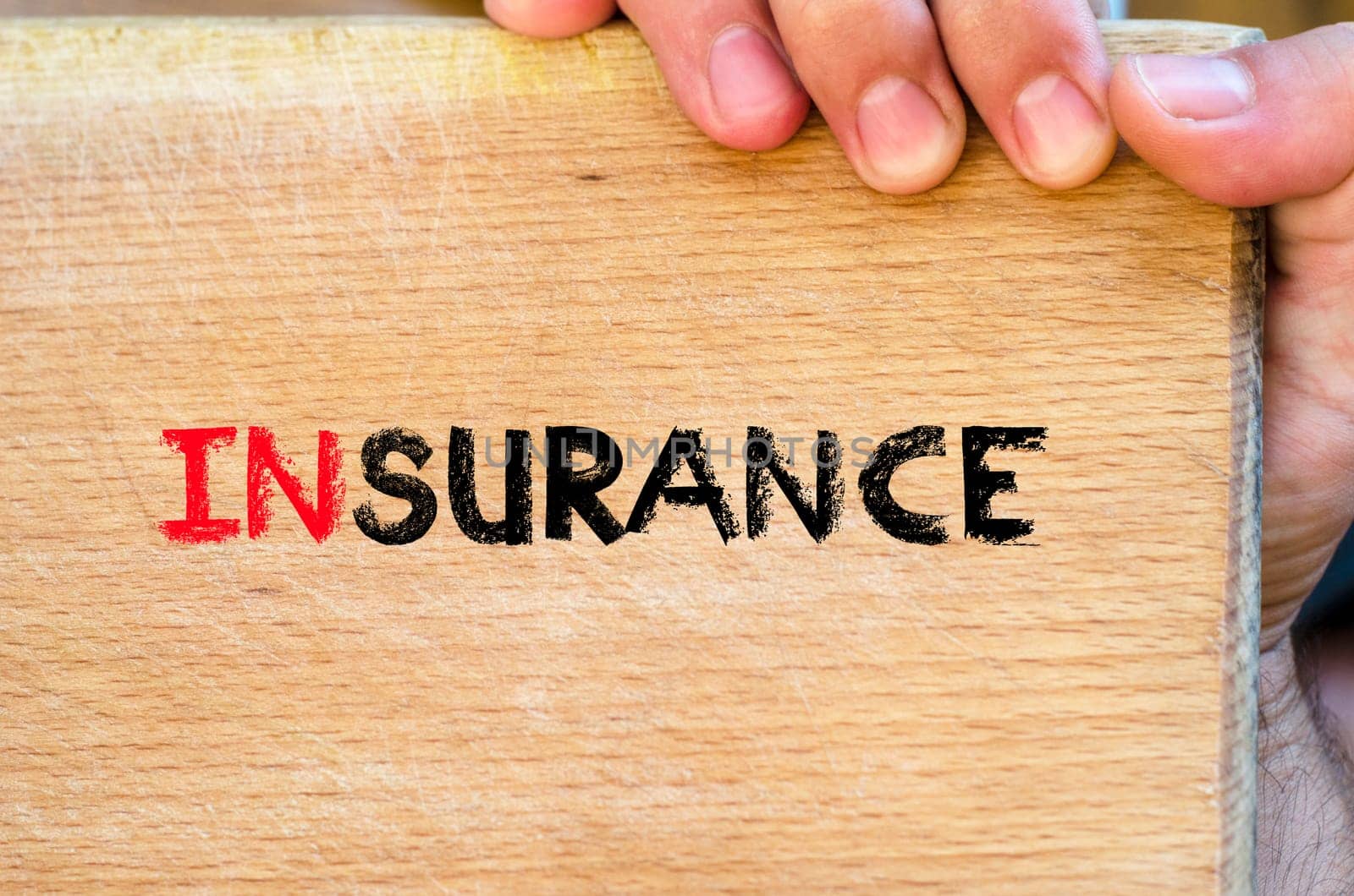 Human hand over wooden background and insurance text concept