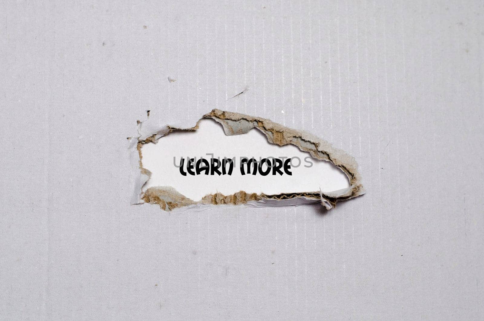 The word learn more appearing behind torn paper