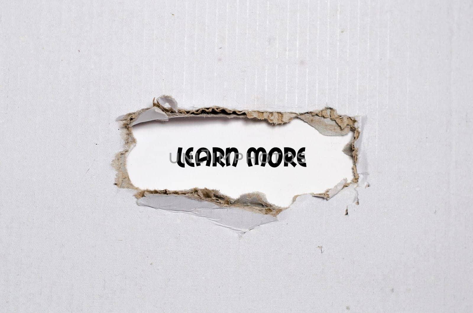 The word learn more appearing behind torn paper