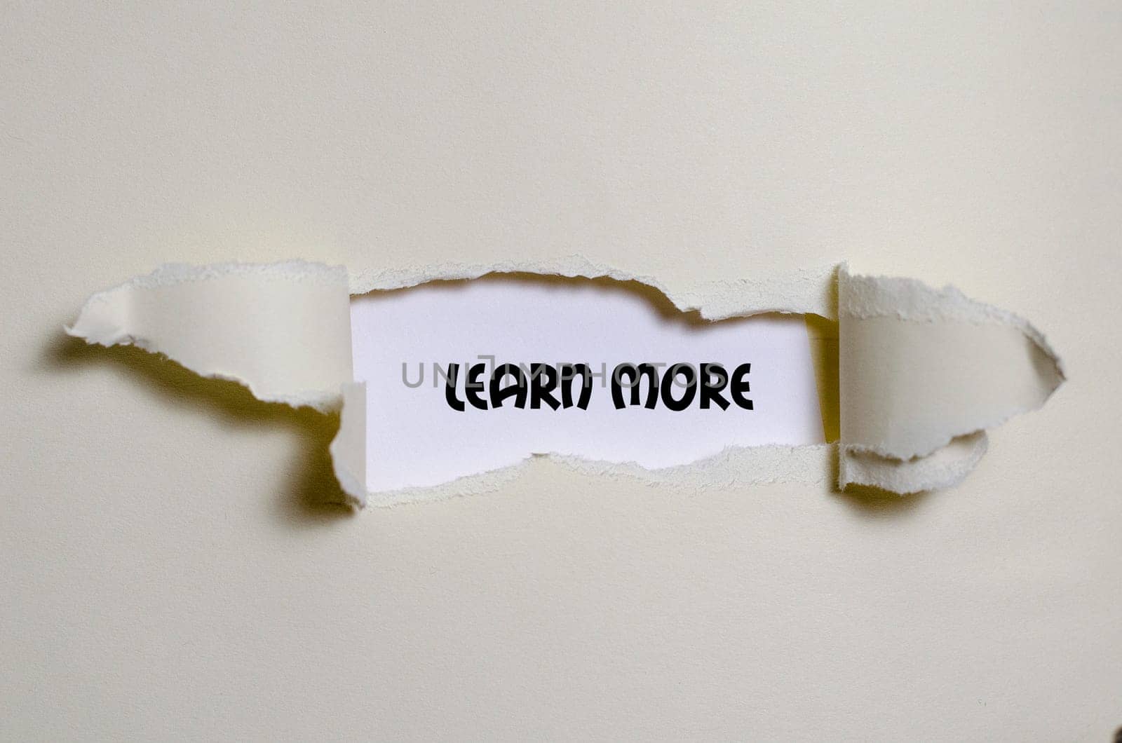 The word learn more appearing behind torn paper