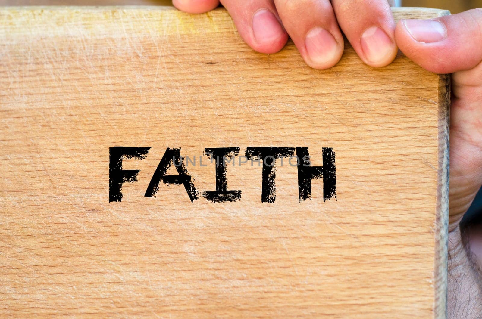 Human hand over wooden background and faith text concept