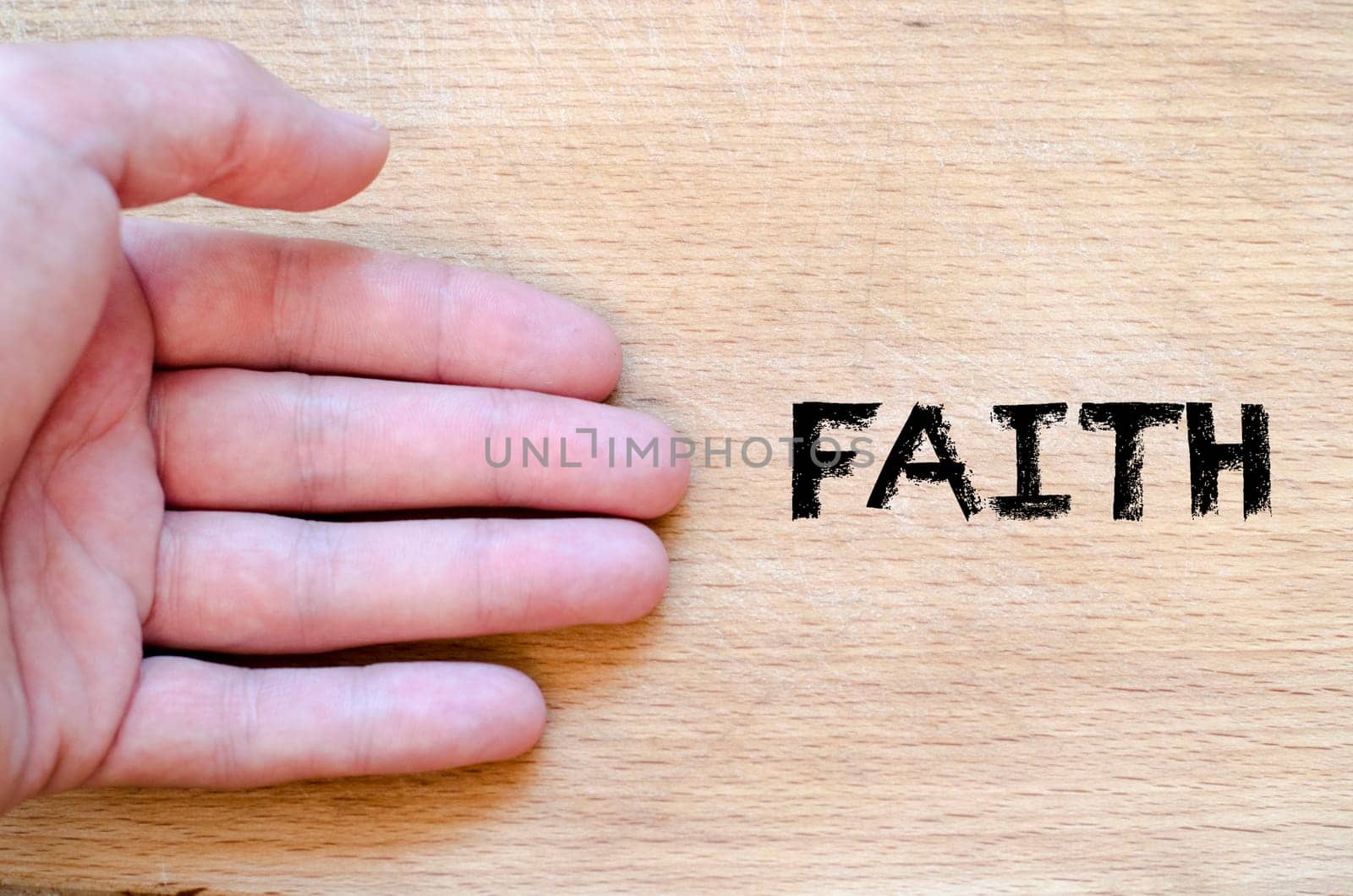 Human hand over wooden background and faith text concept