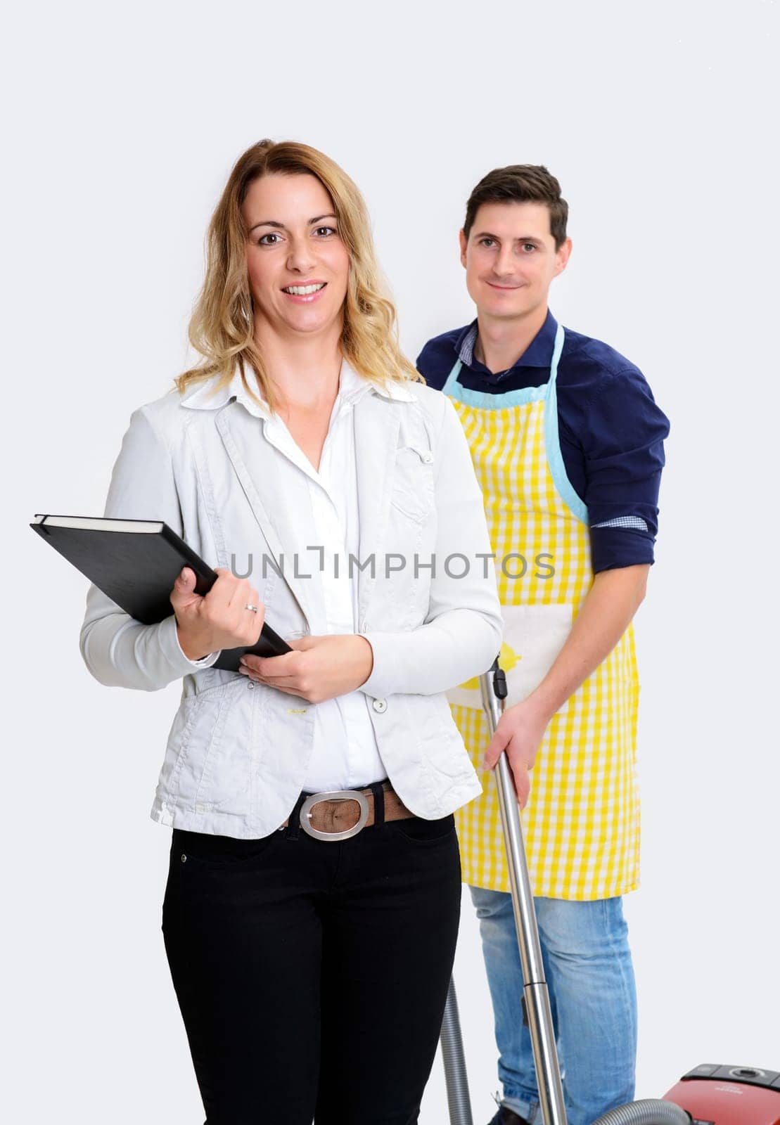 young beautiful businesswoman and her husband with vacuum cleaner in background