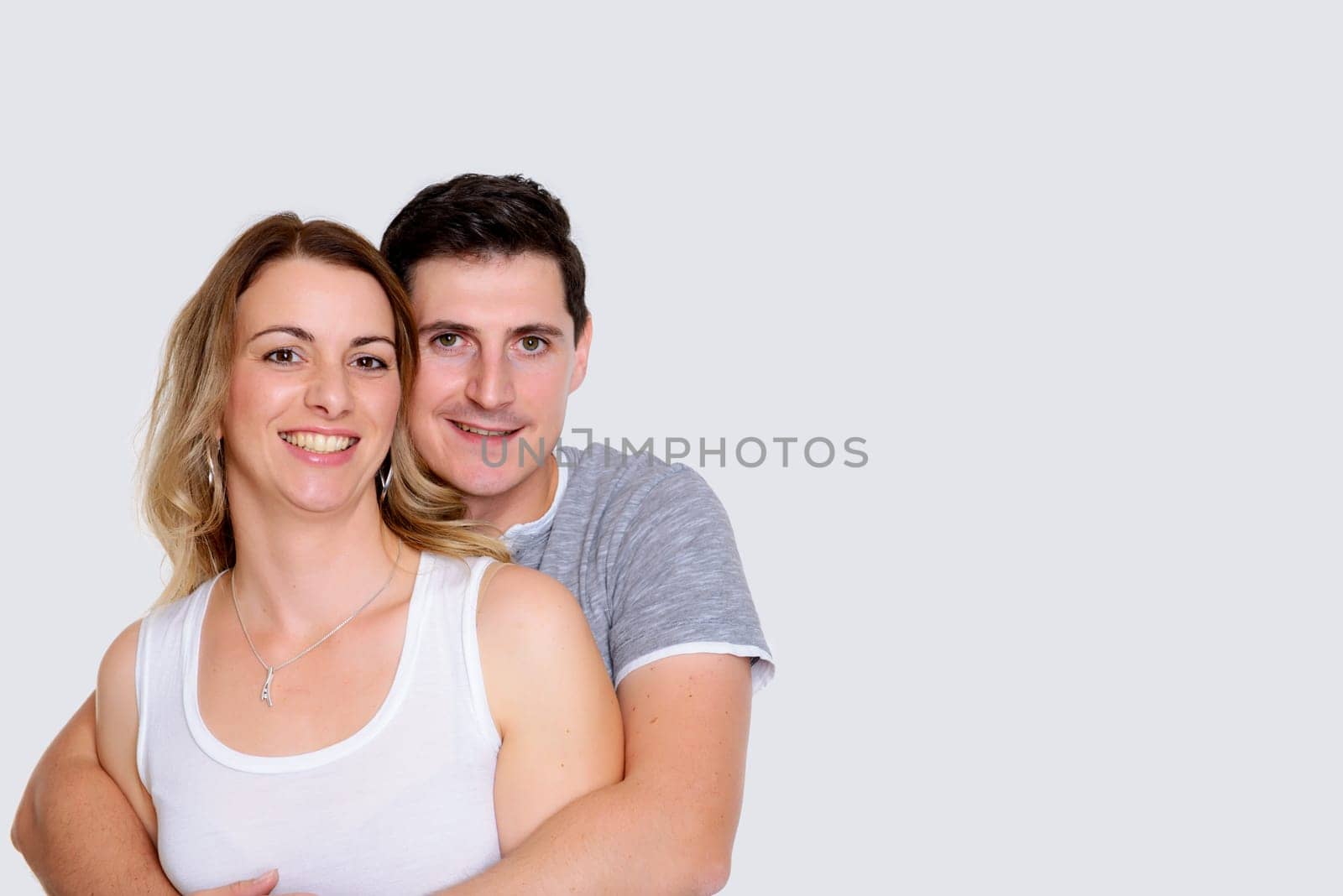 young couple in an embrace in front of white background