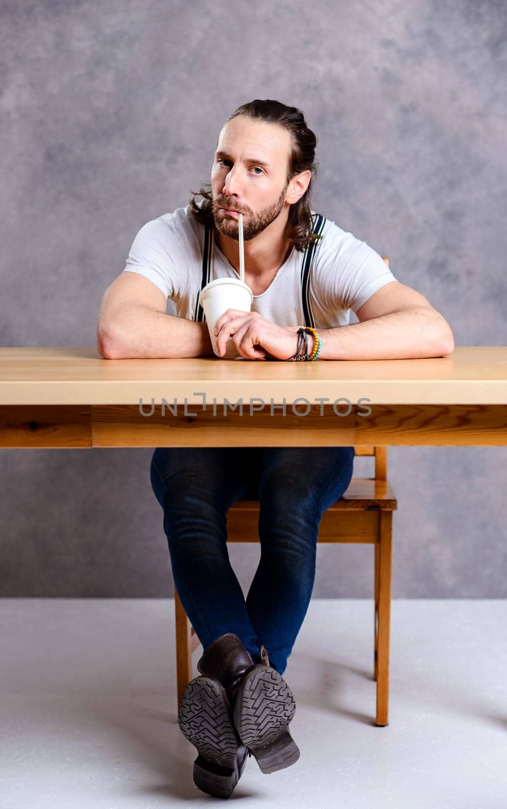 young man drinking soft drink in front of gray background