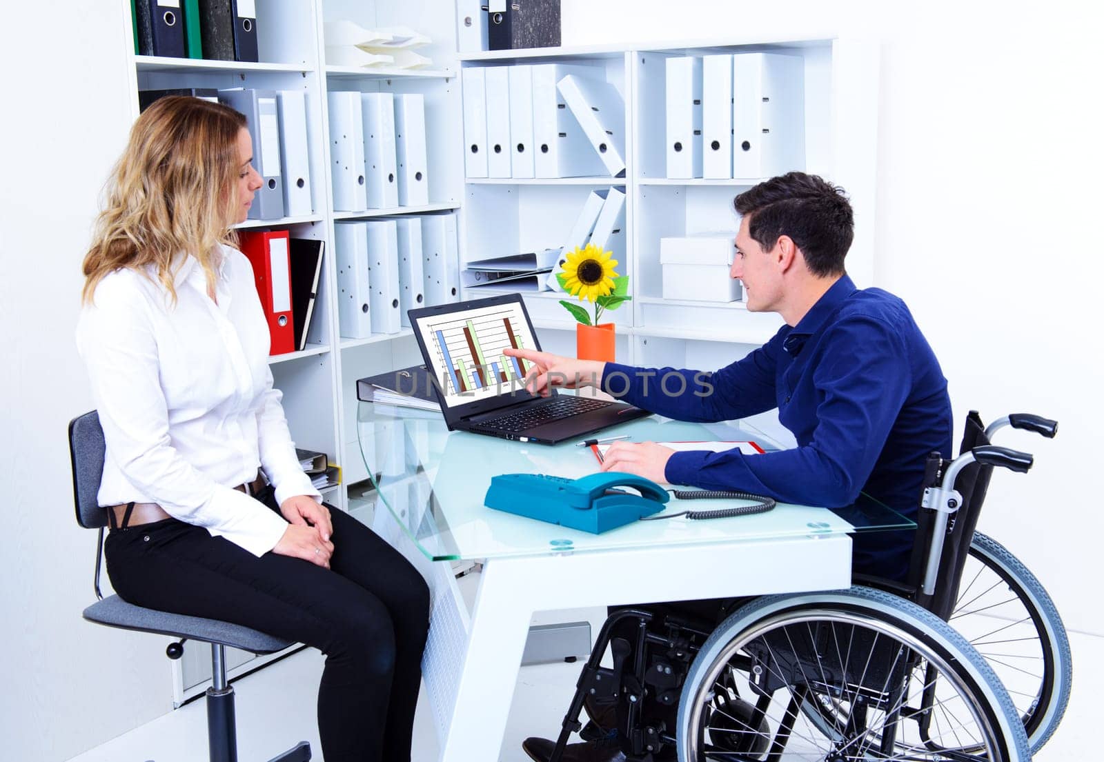 disabled businessman in wheelchair and his female colleague