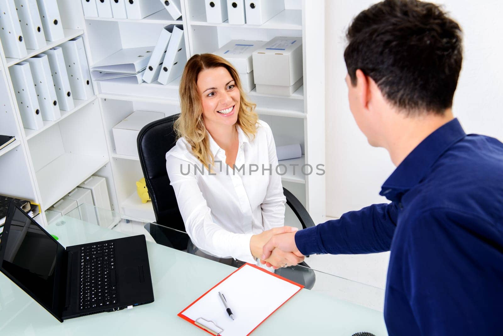 young businesswoman greeting male client in her office
