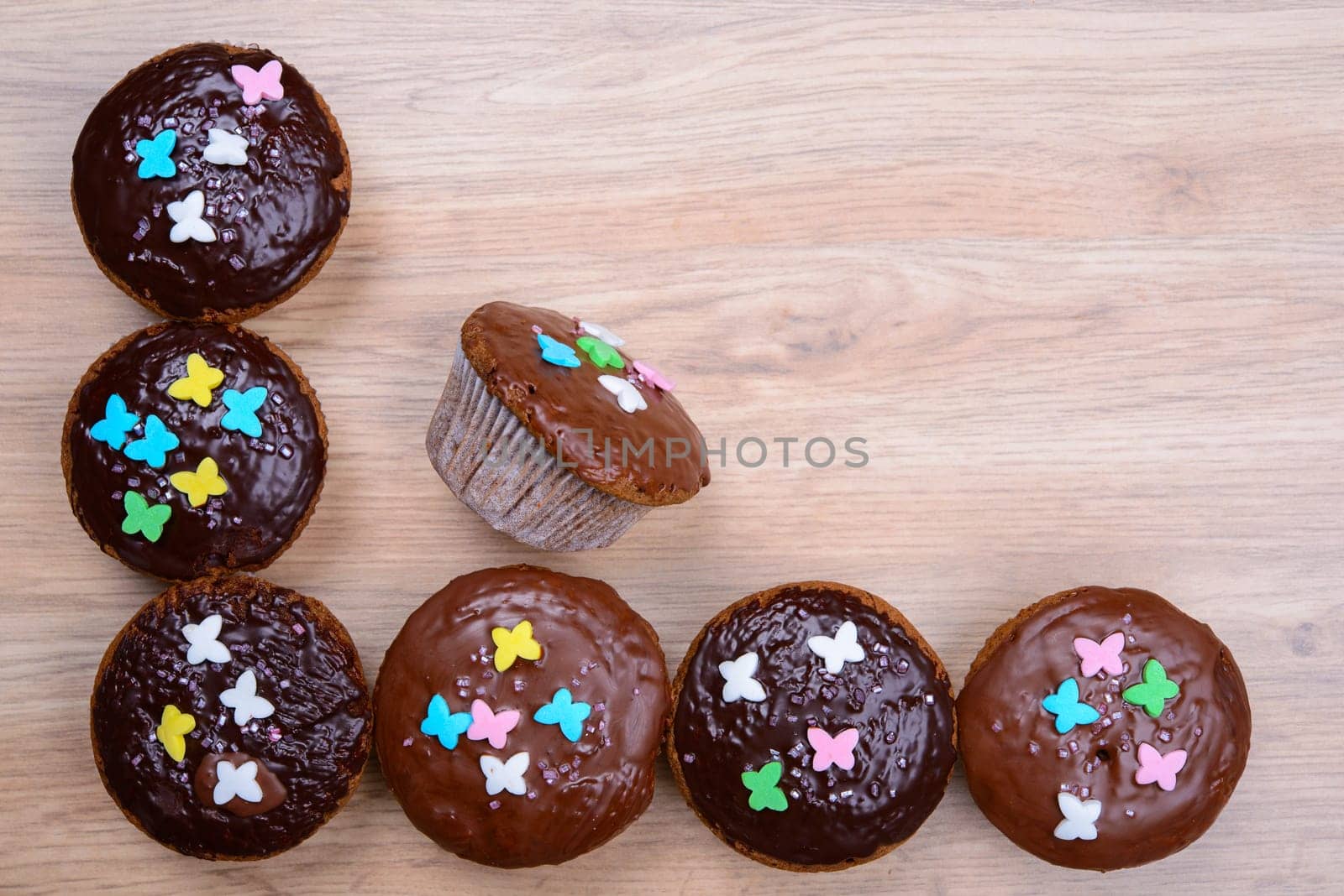 chocolate muffins with colorful decoration on wooden ground