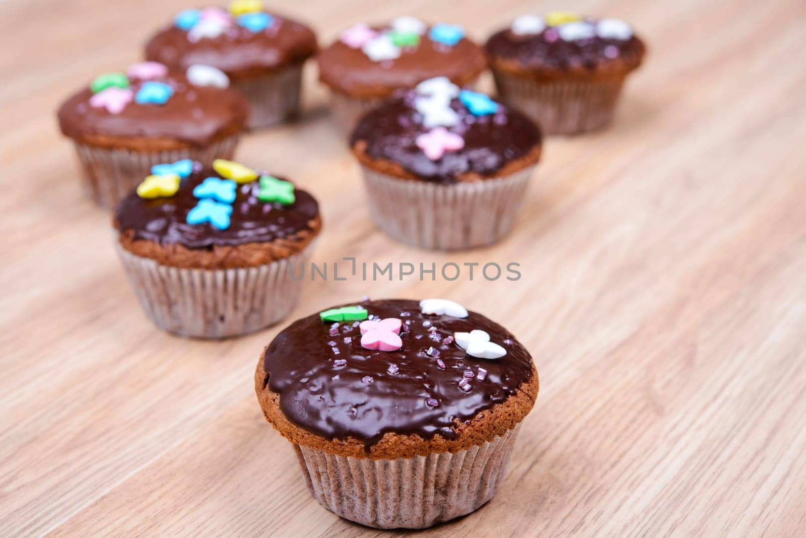 chocolate muffins with colorful decoration on wooden ground