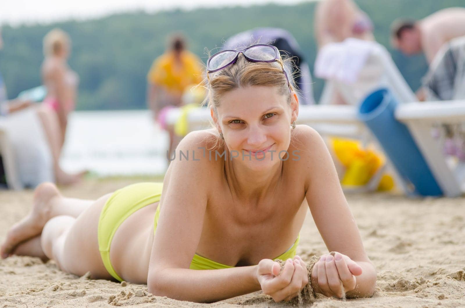 A young girl picked up sand lying on his stomach on the sandy beach