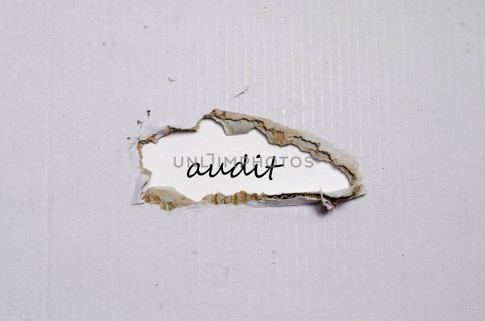 The word audit appearing behind torn paper