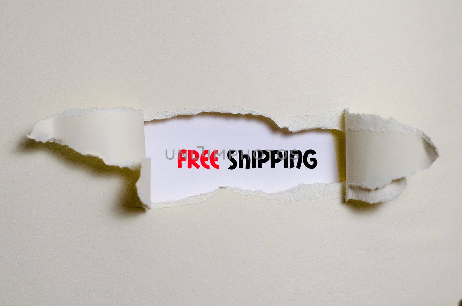 The word free shipping appearing behind torn paper