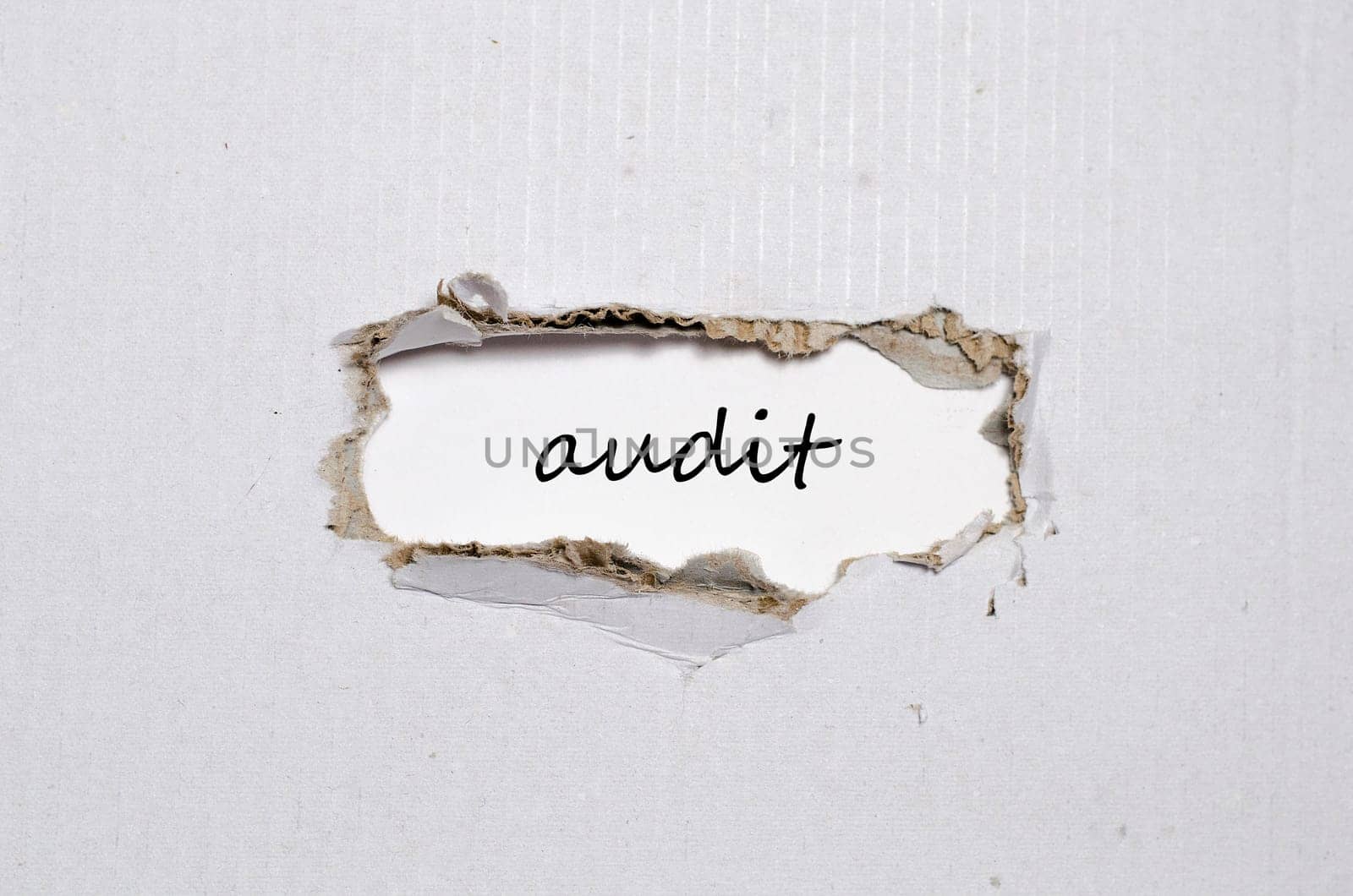 The word audit appearing behind torn paper