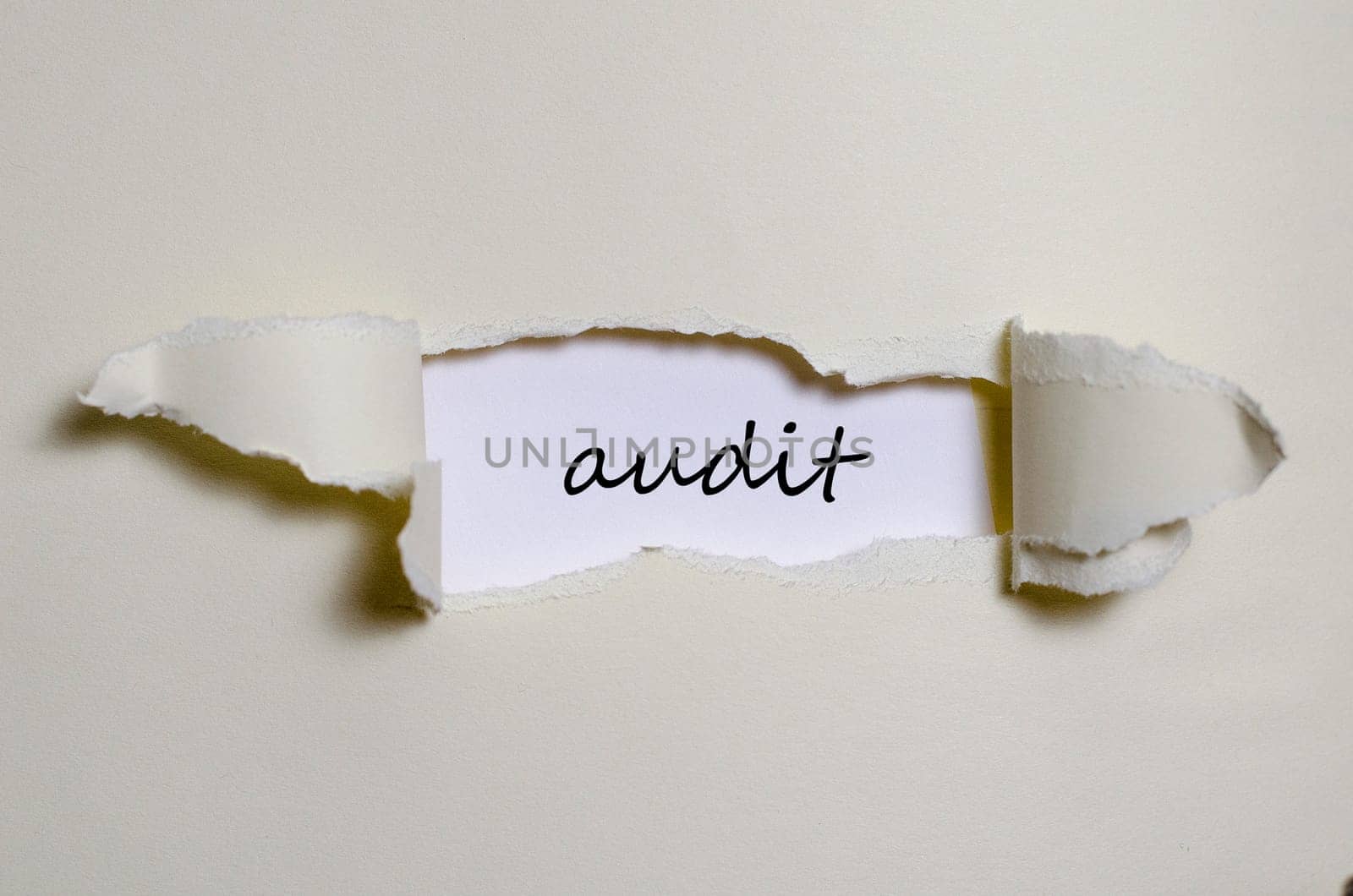 The word audit appearing behind torn paper
