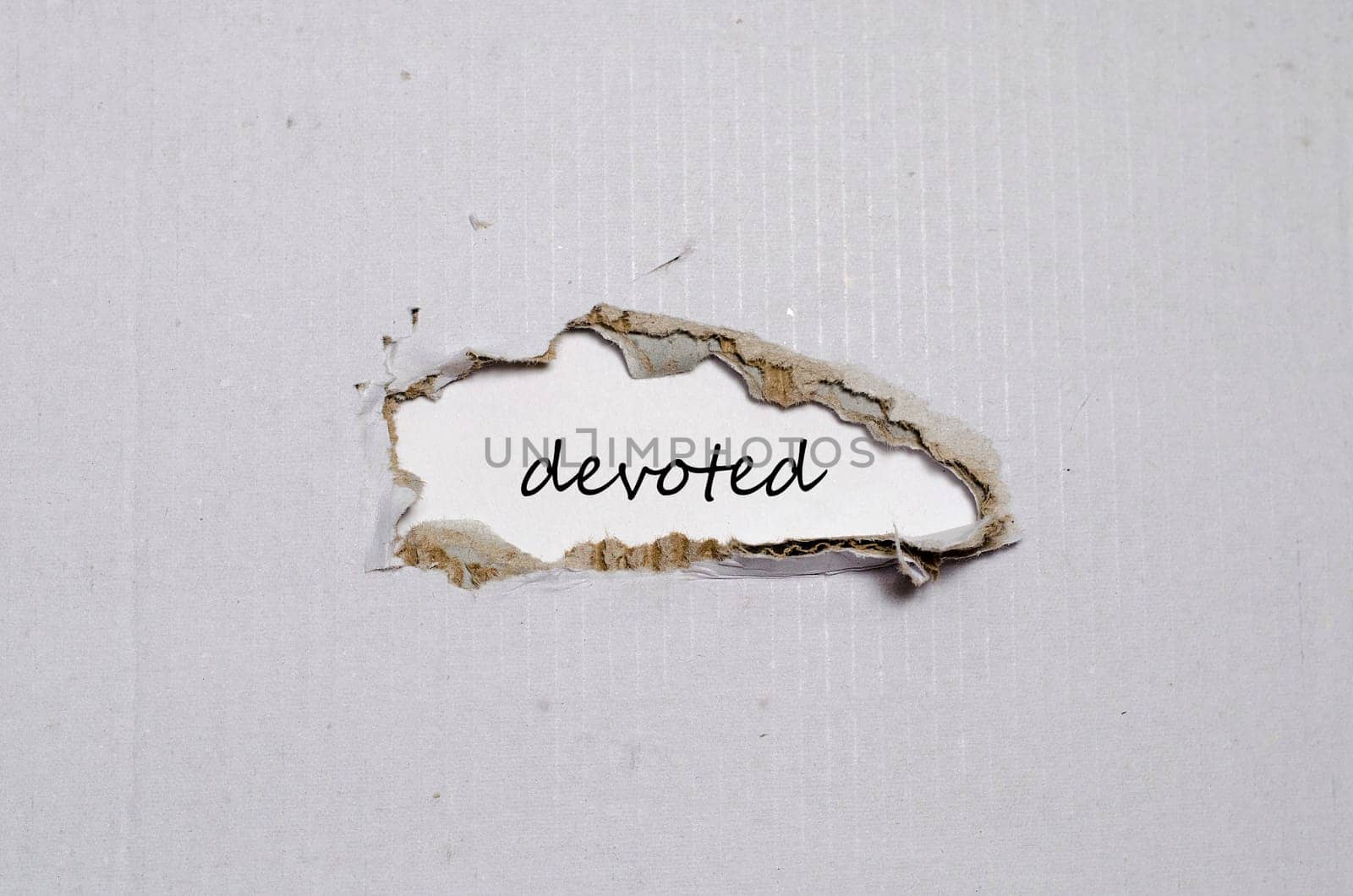 The word devoted appearing behind torn paper