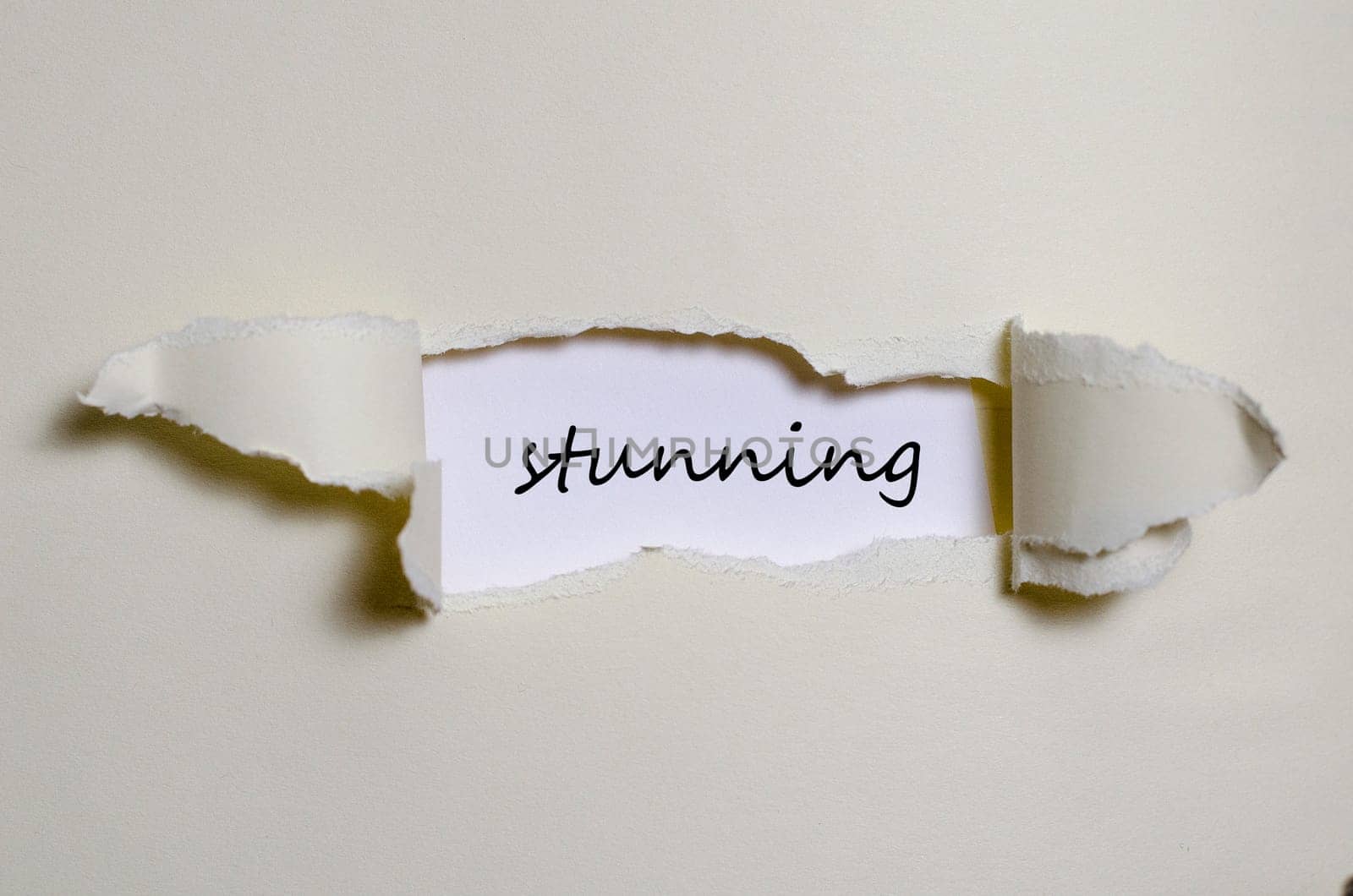 The word stunning appearing behind torn paper