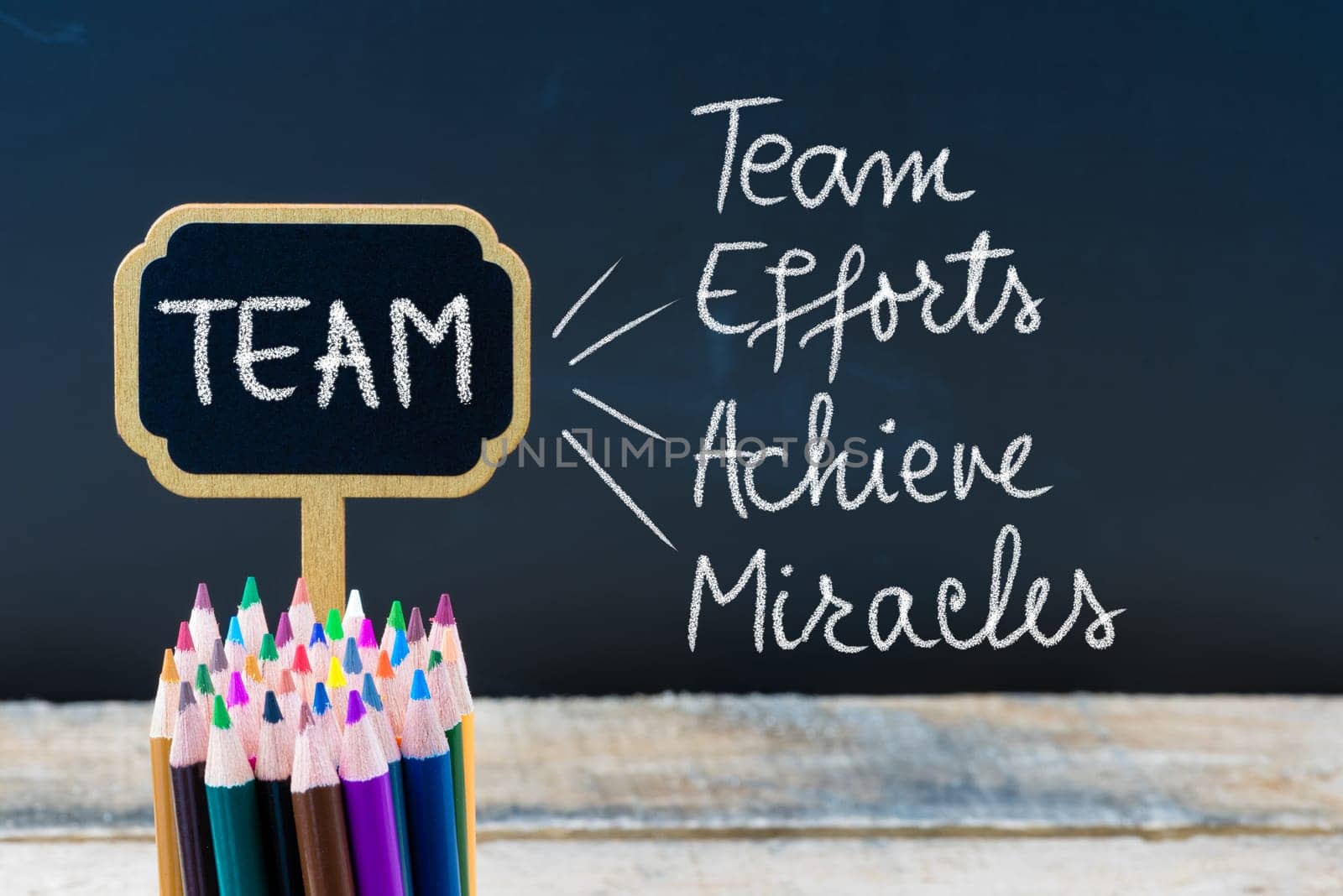 Business Acronym TEAM as Team Efforts Achieve Miracles written with chalk on wooden mini blackboard labels and chalkboard background.