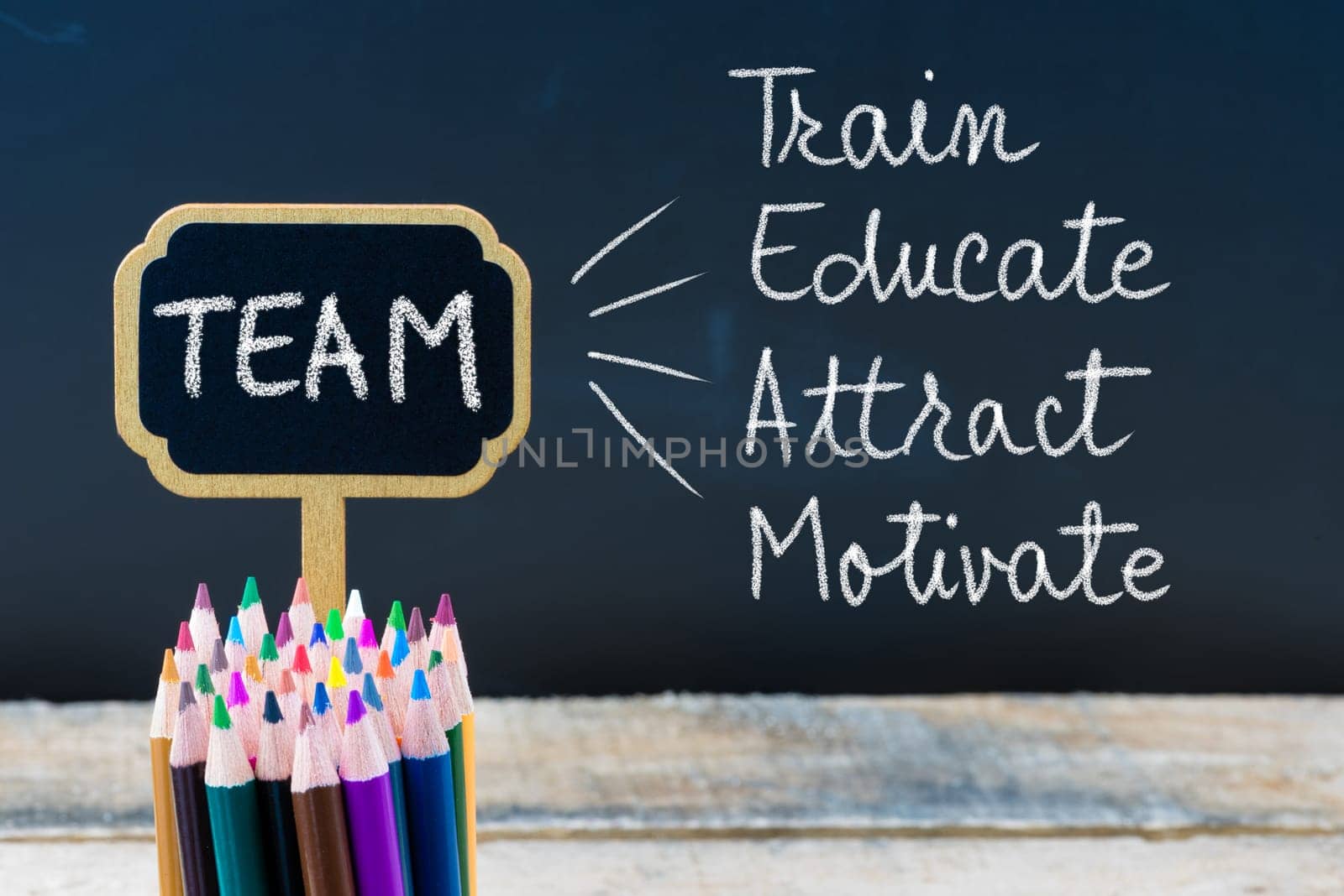 Business Acronym TEAM Train Educate Attract Motivate written with chalk on wooden mini blackboard labels and chalkboard background.