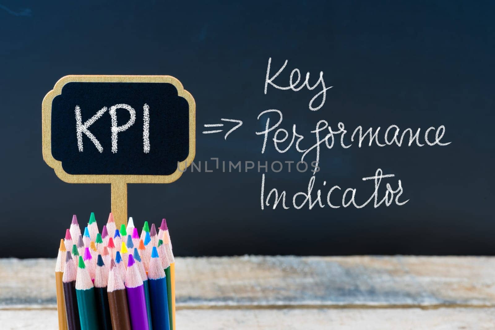 Business Acronym KPI Key Performance Indicator written with chalk on wooden mini blackboard labels and chalkboard background.