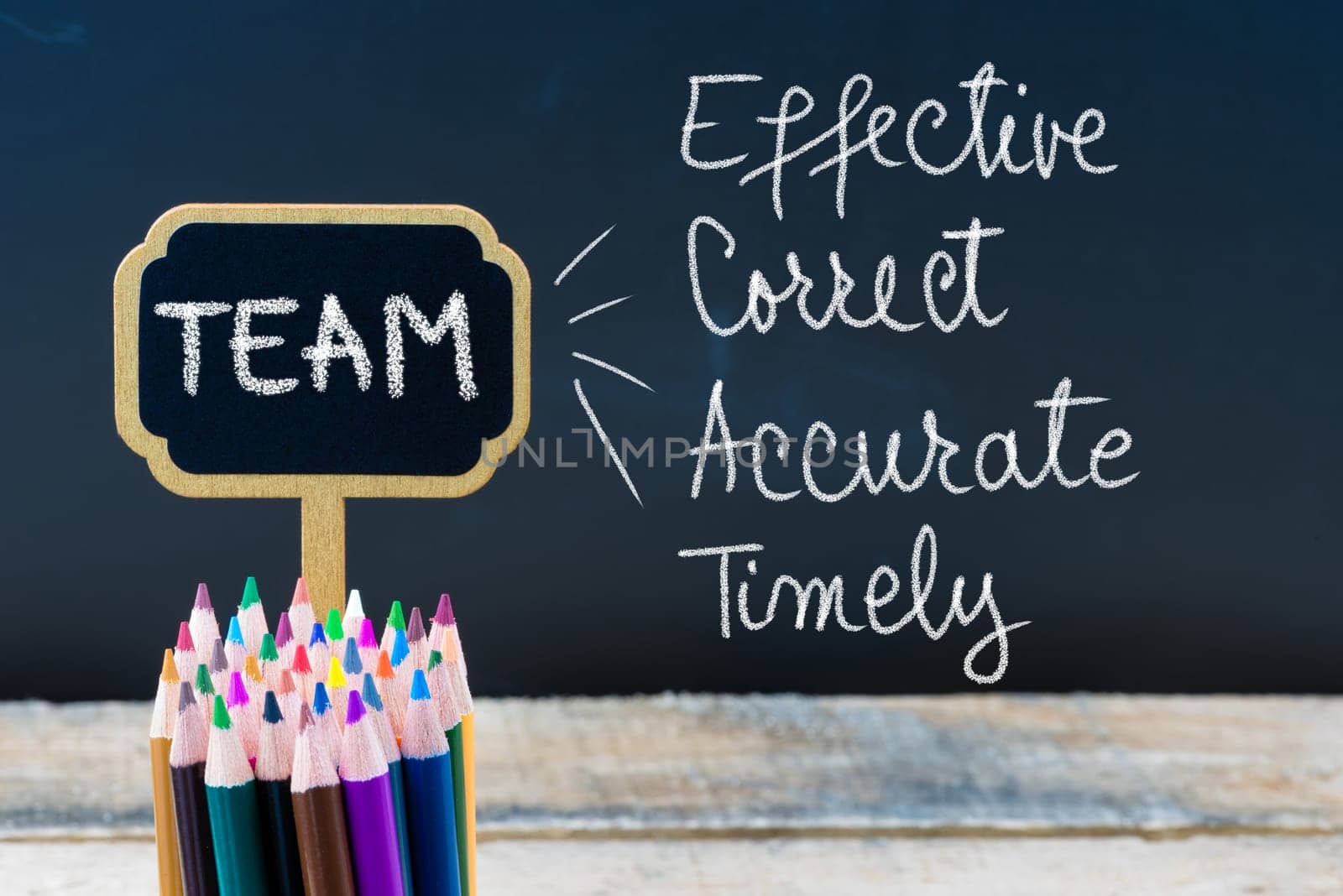 Business Acronym TEAM Effective Correct Accurate Timely written with chalk on wooden mini blackboard labels and chalkboard background.